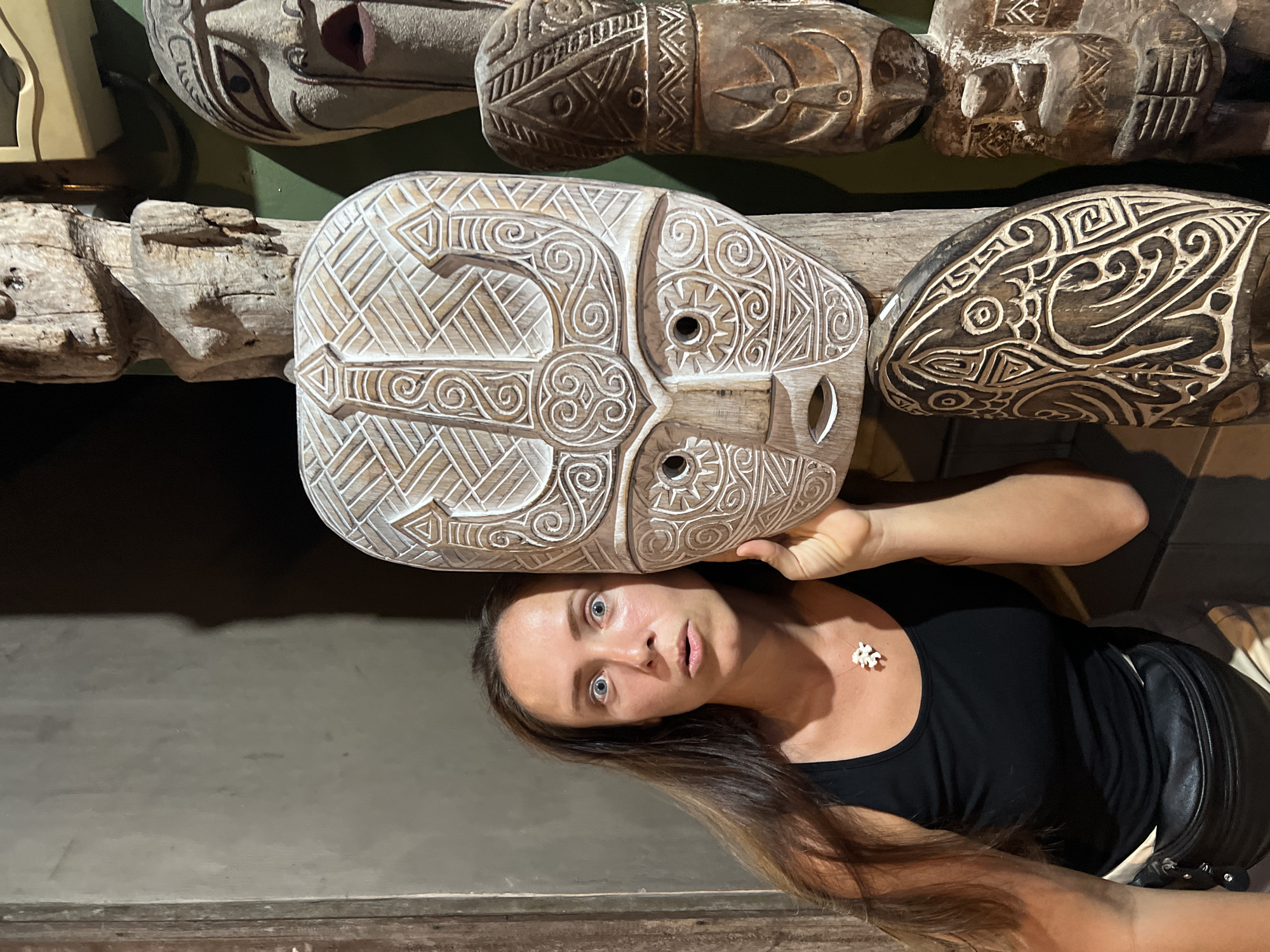 Tourist examines traditional carved masks at Ubud craft display