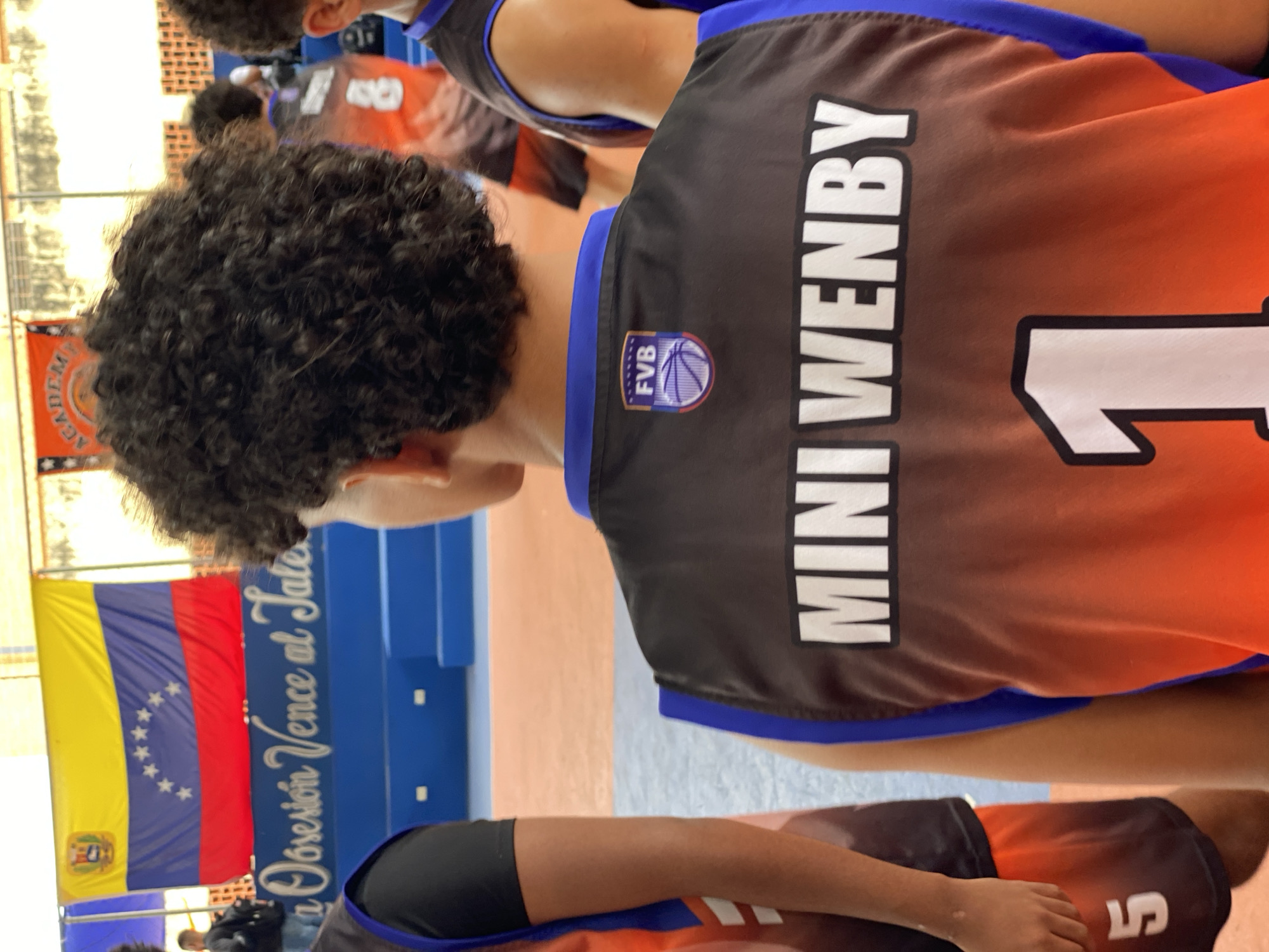 Youth basketball game played at Valencia court with inspirational mural