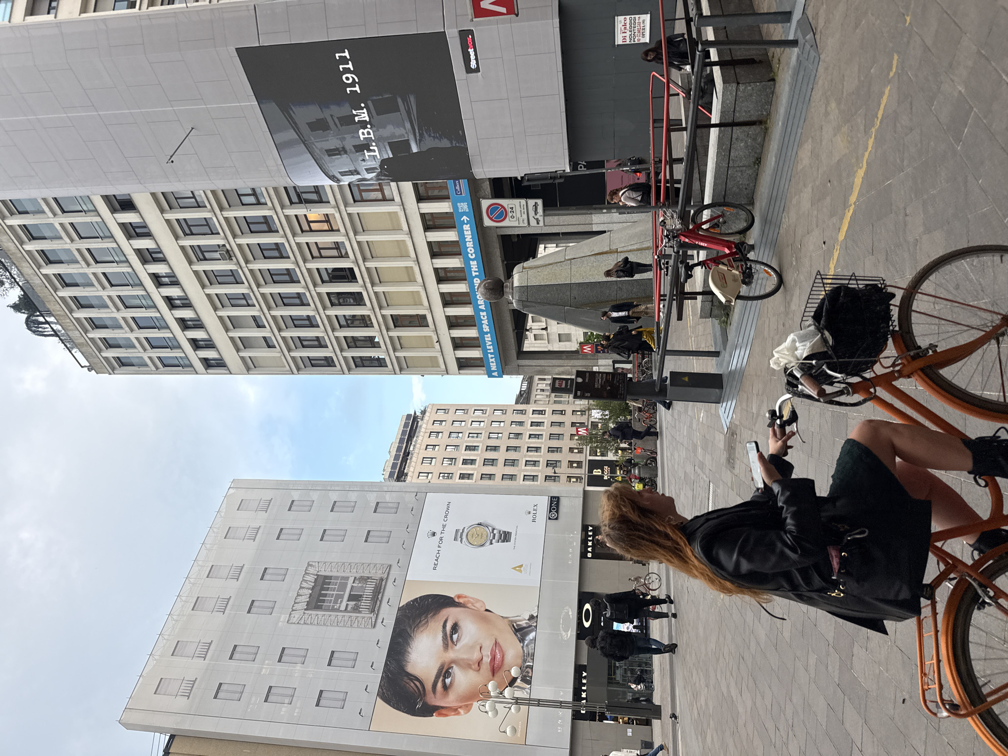 Woman uses phone while on bicycle in Milan street