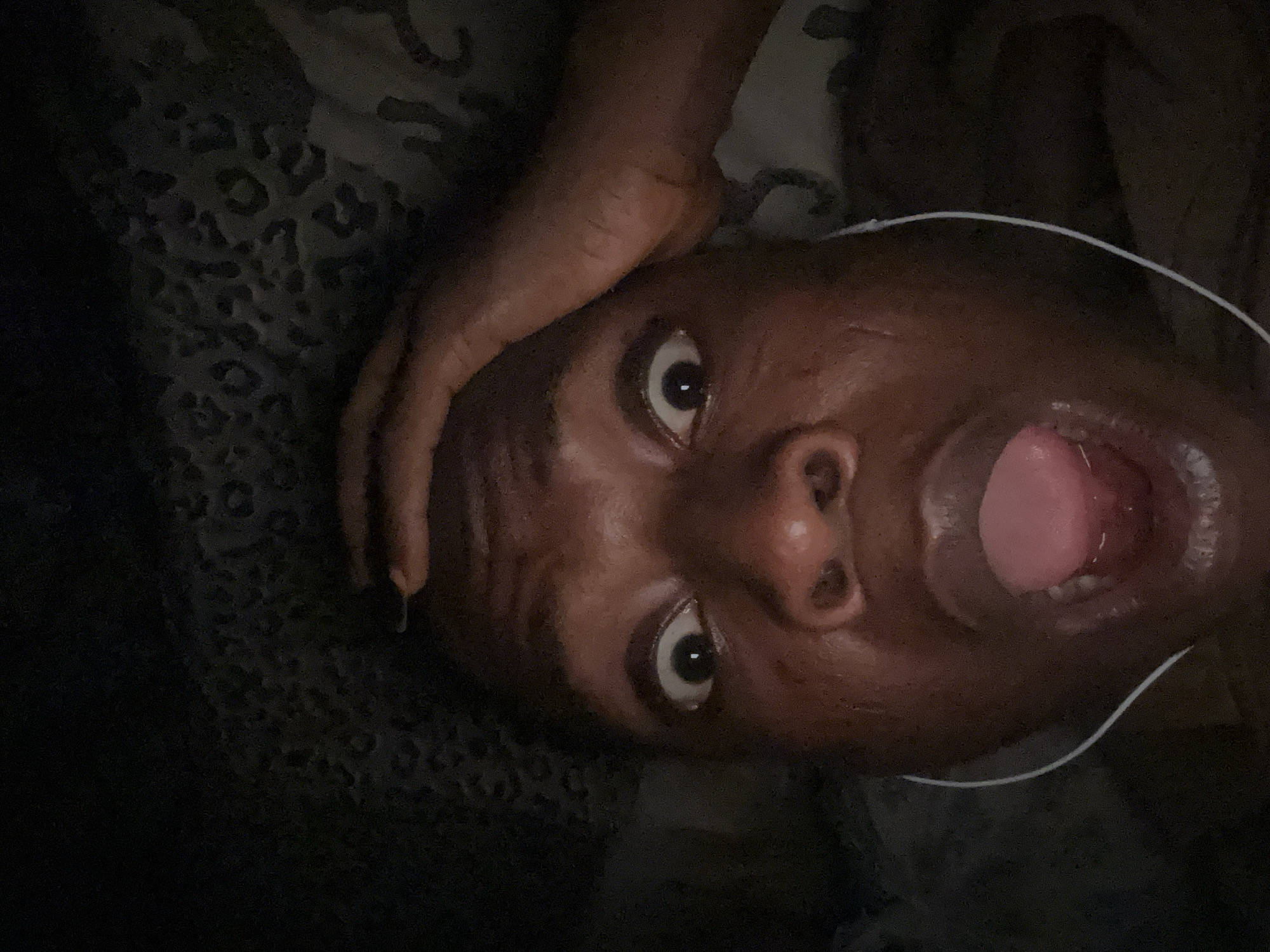 Person photographed showing surprise while lying in bed with headphones