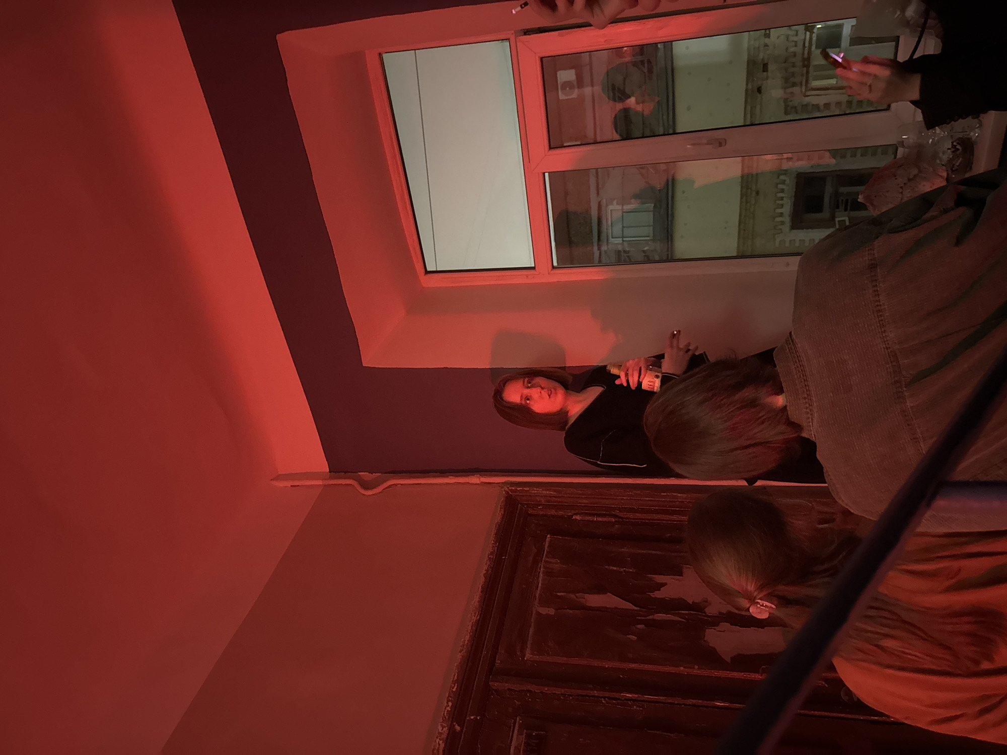 Social gathering documented in red-lit Moscow interior during evening hours