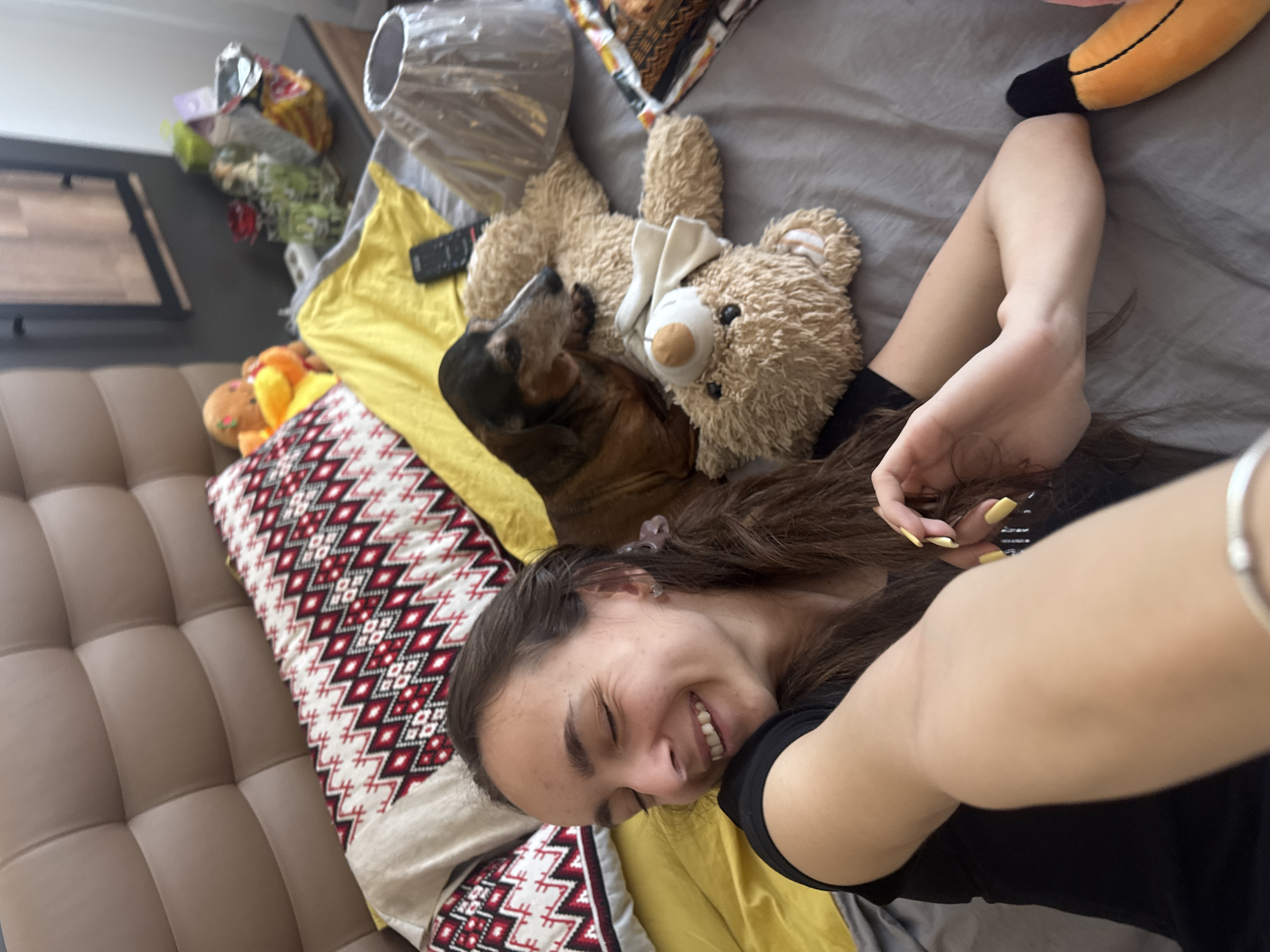 Woman enjoys morning bedroom time with dog and toys