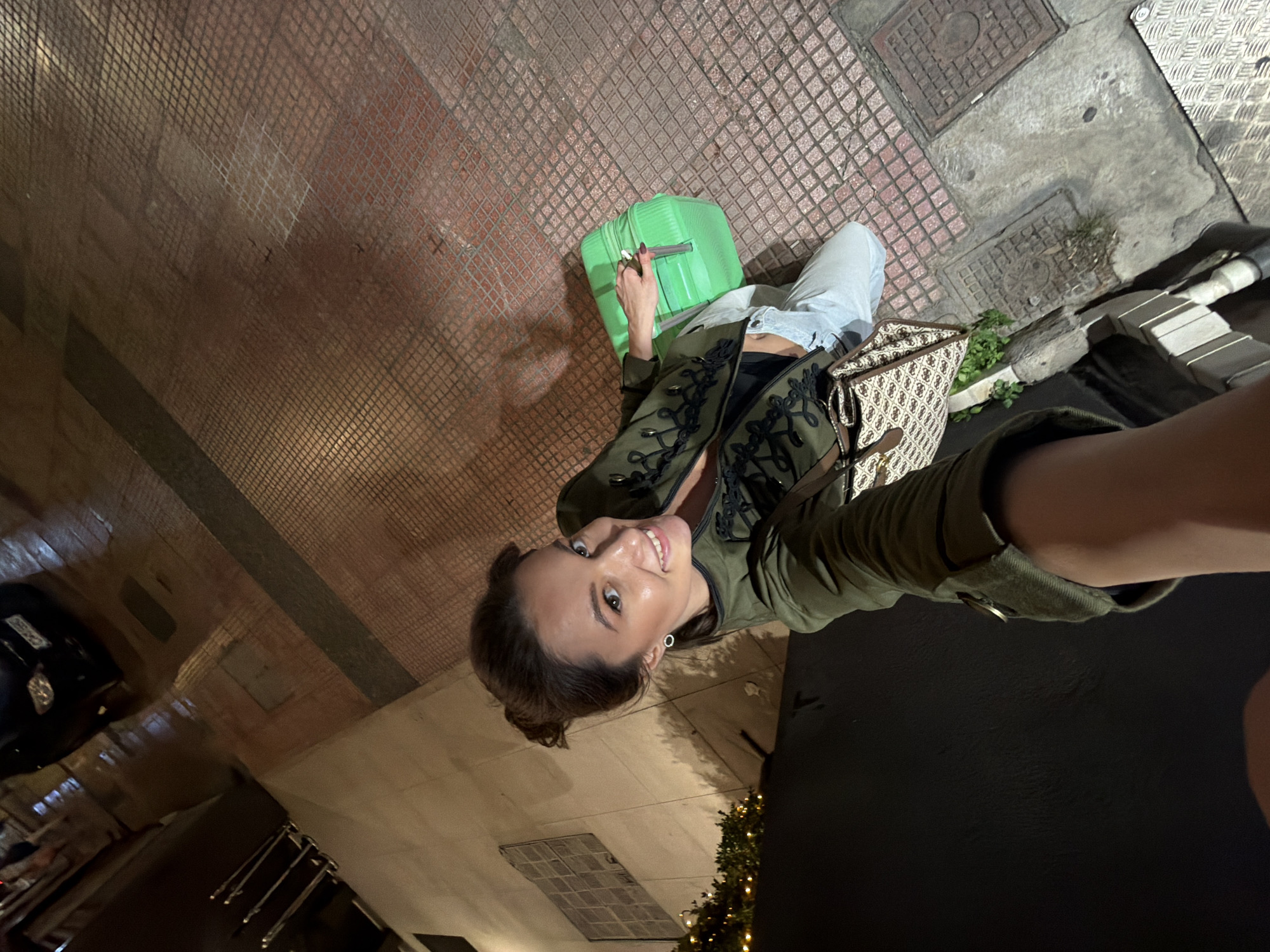 Woman takes nighttime selfie on Athens street with parked scooters