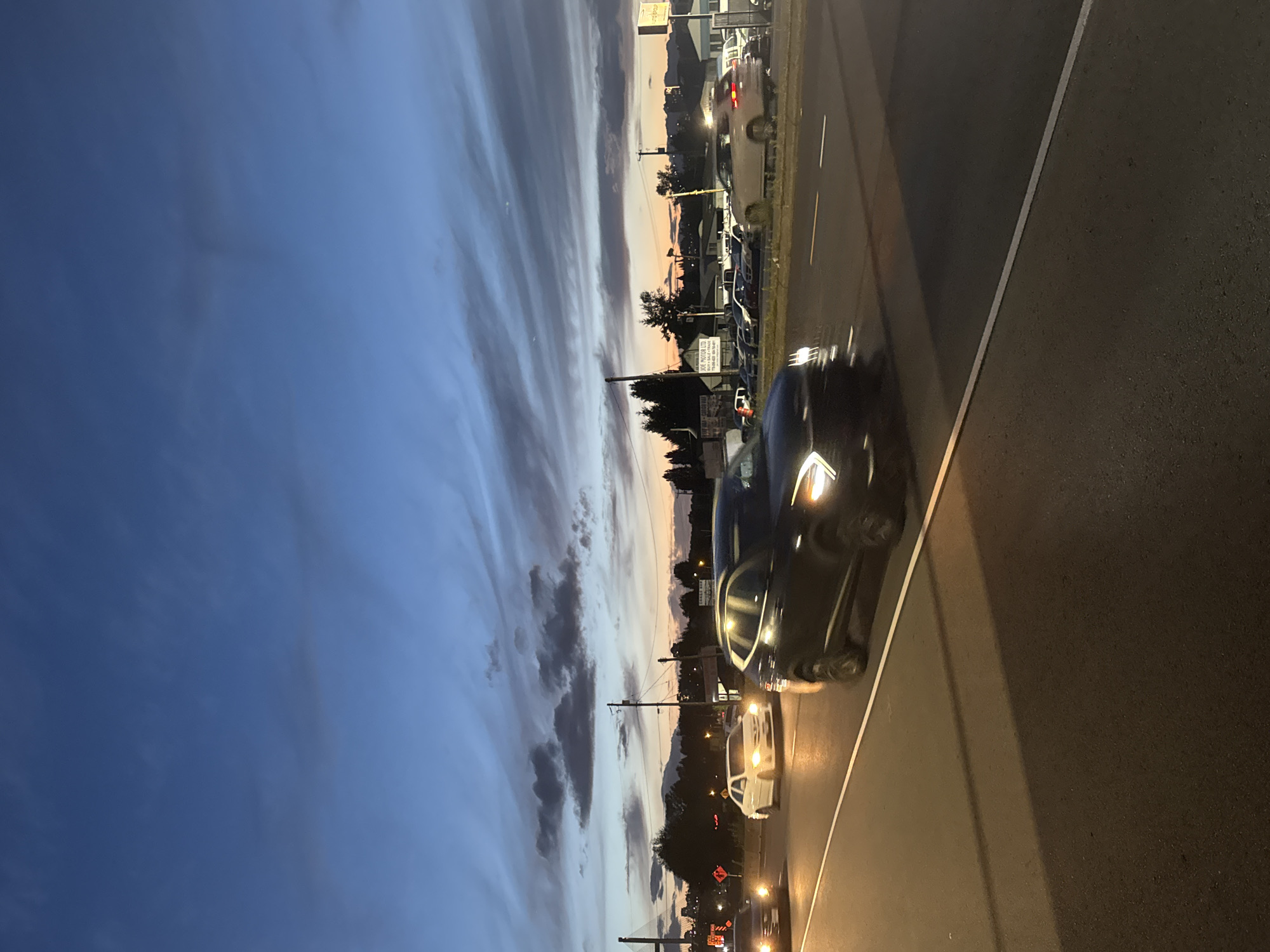 Dusk along a Surrey highway strip near a used car lot