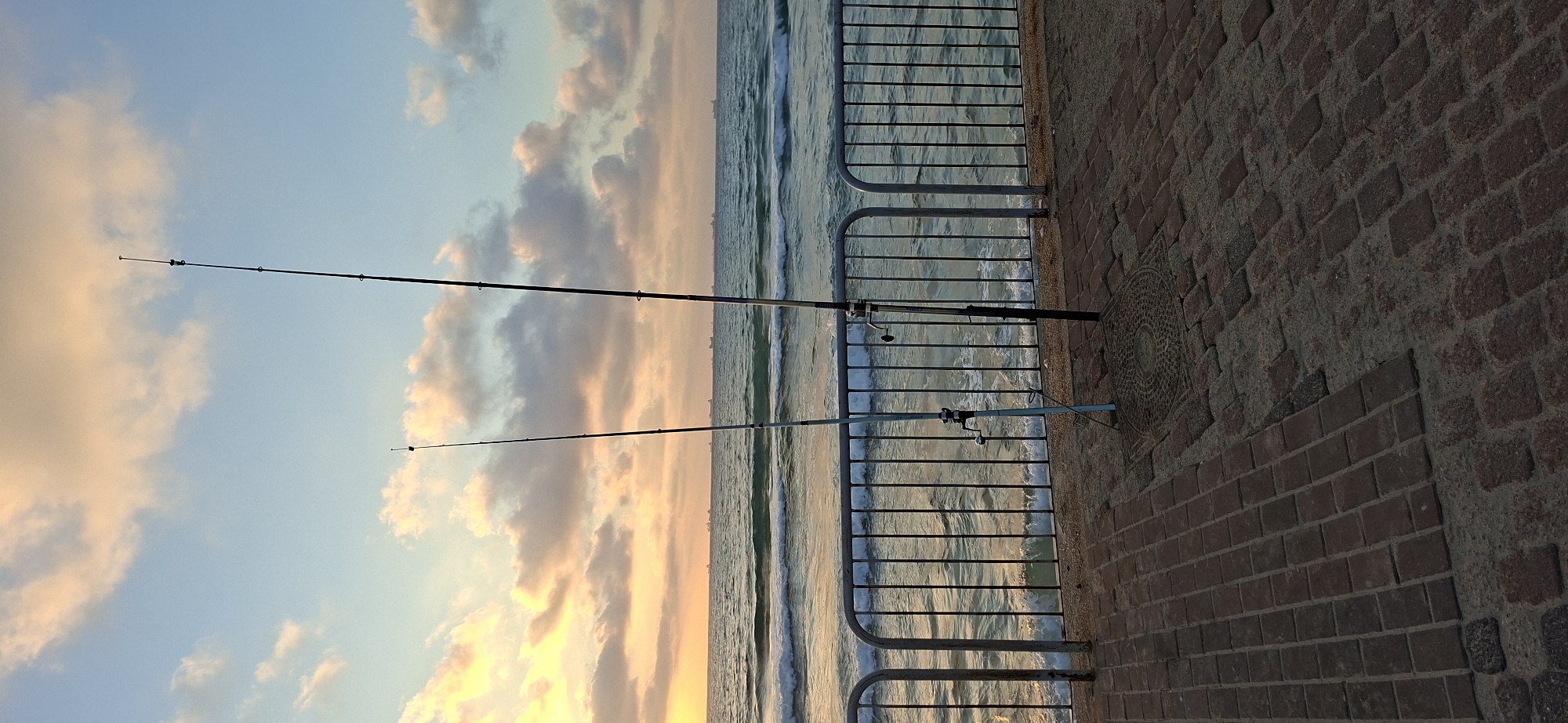 Fishing and shoreline views at sunset along a city coast