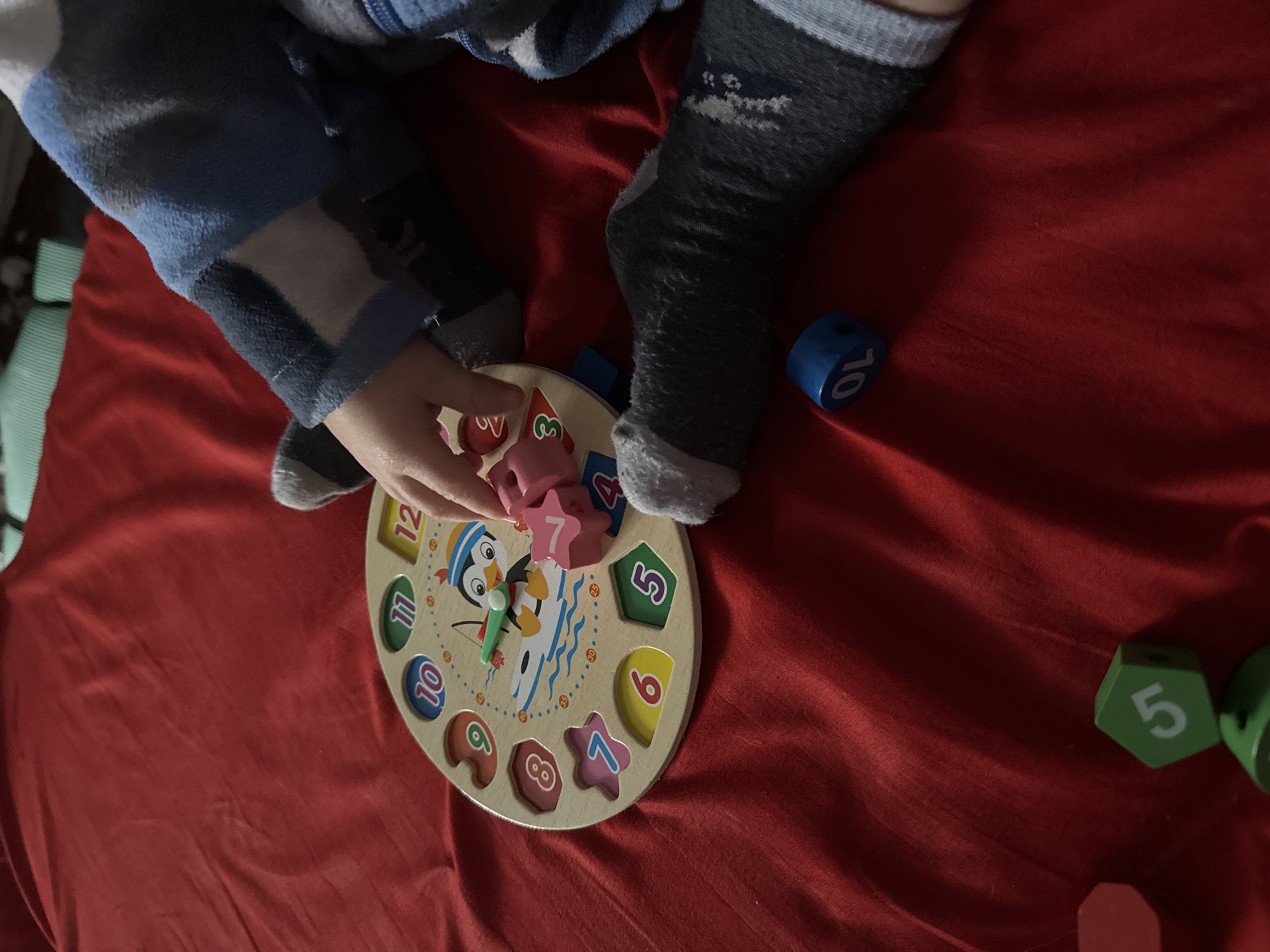 Child plays with wooden clock puzzle in Donetsk