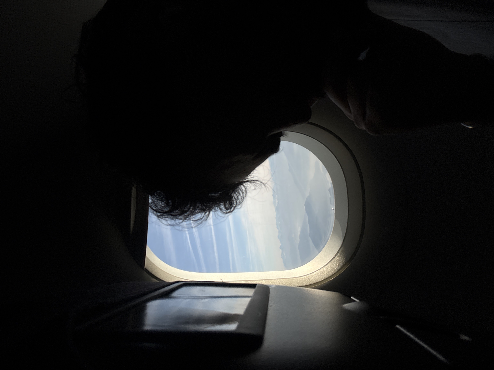 Passenger silhouetted against airplane window captured over northern Italy