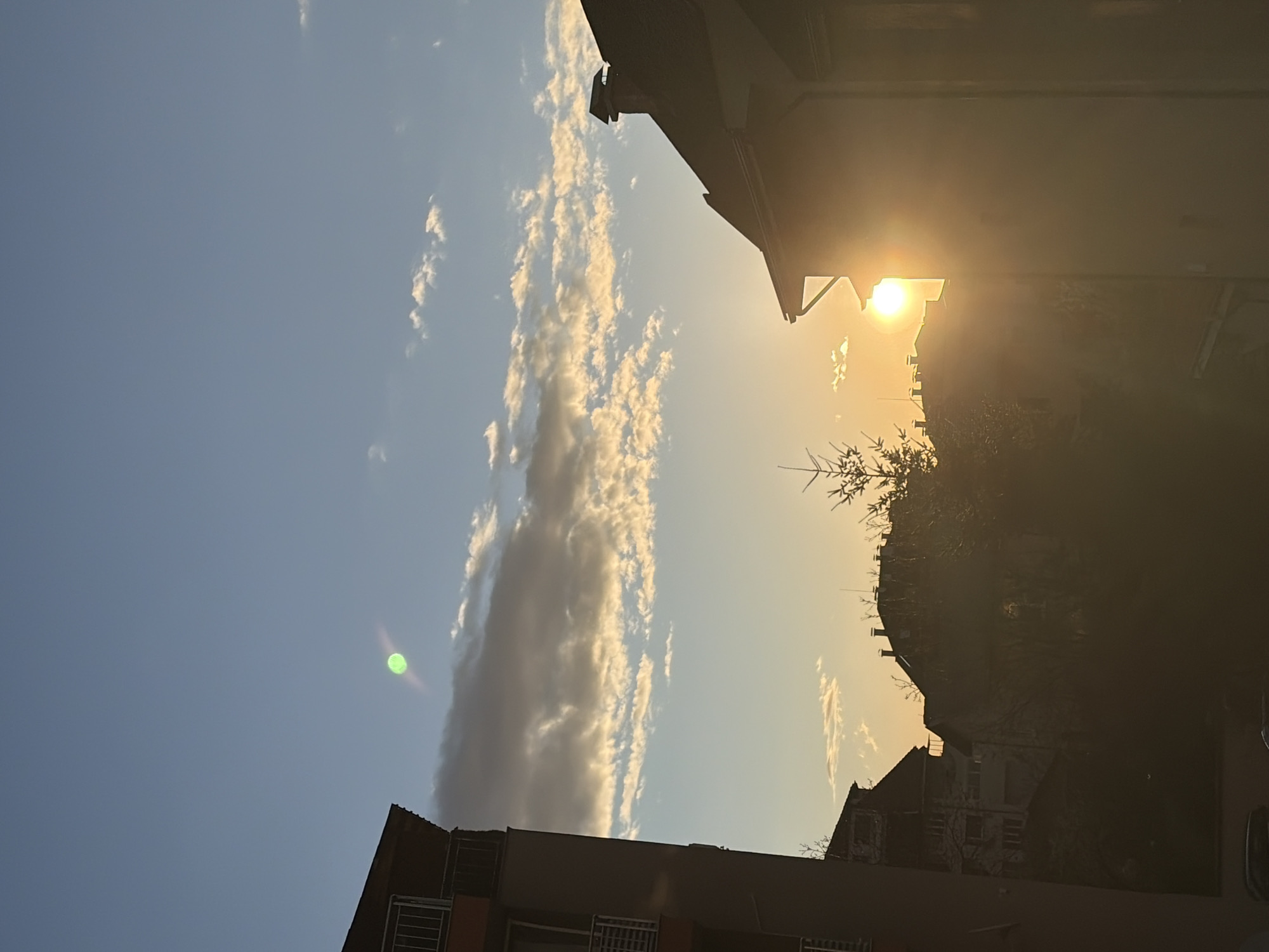 Dawn breaks over Sofia skyline, buildings silhouetted against bright sun