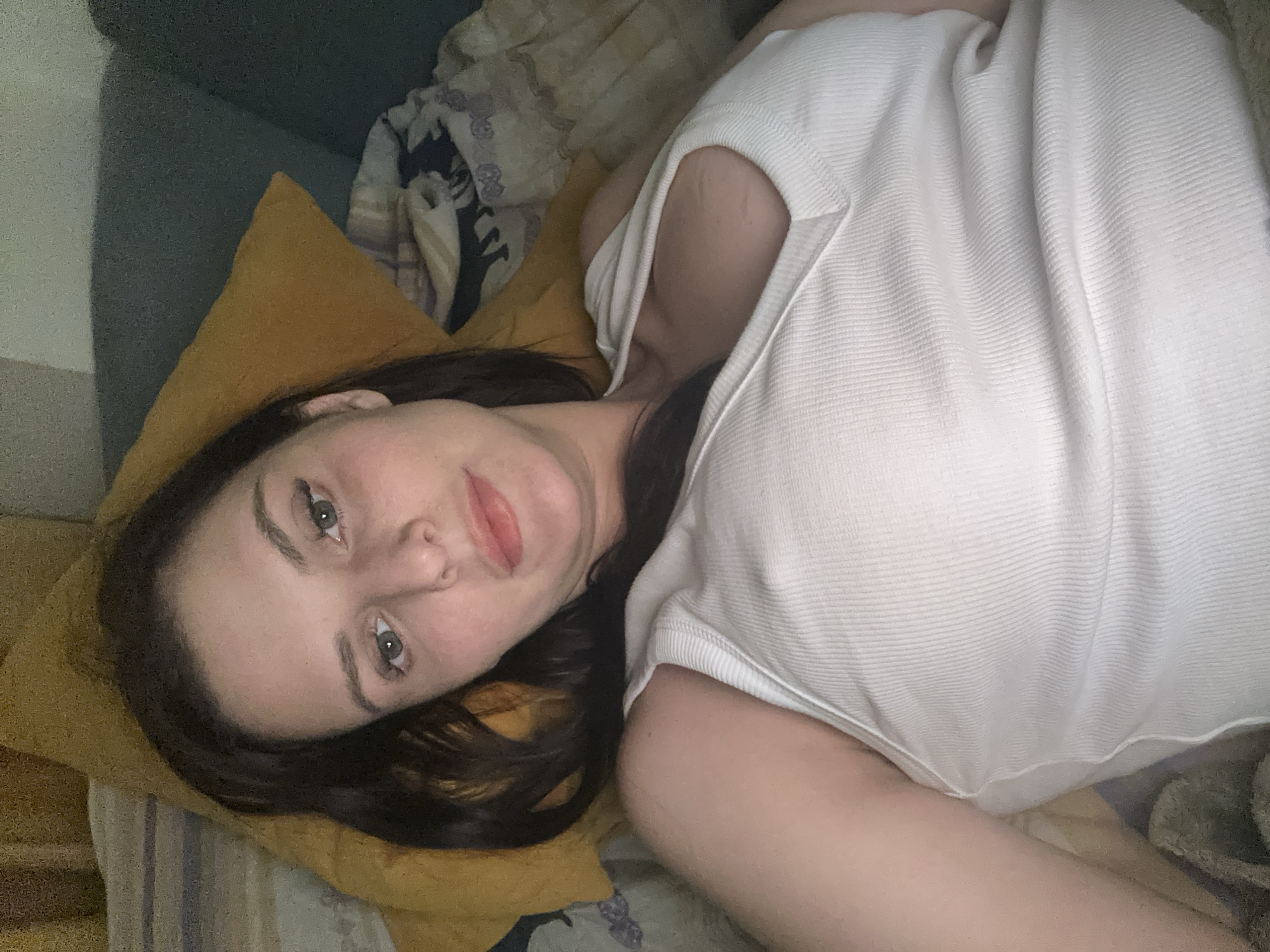 Relaxed close-up selfie on a bed, casual indoor setting.