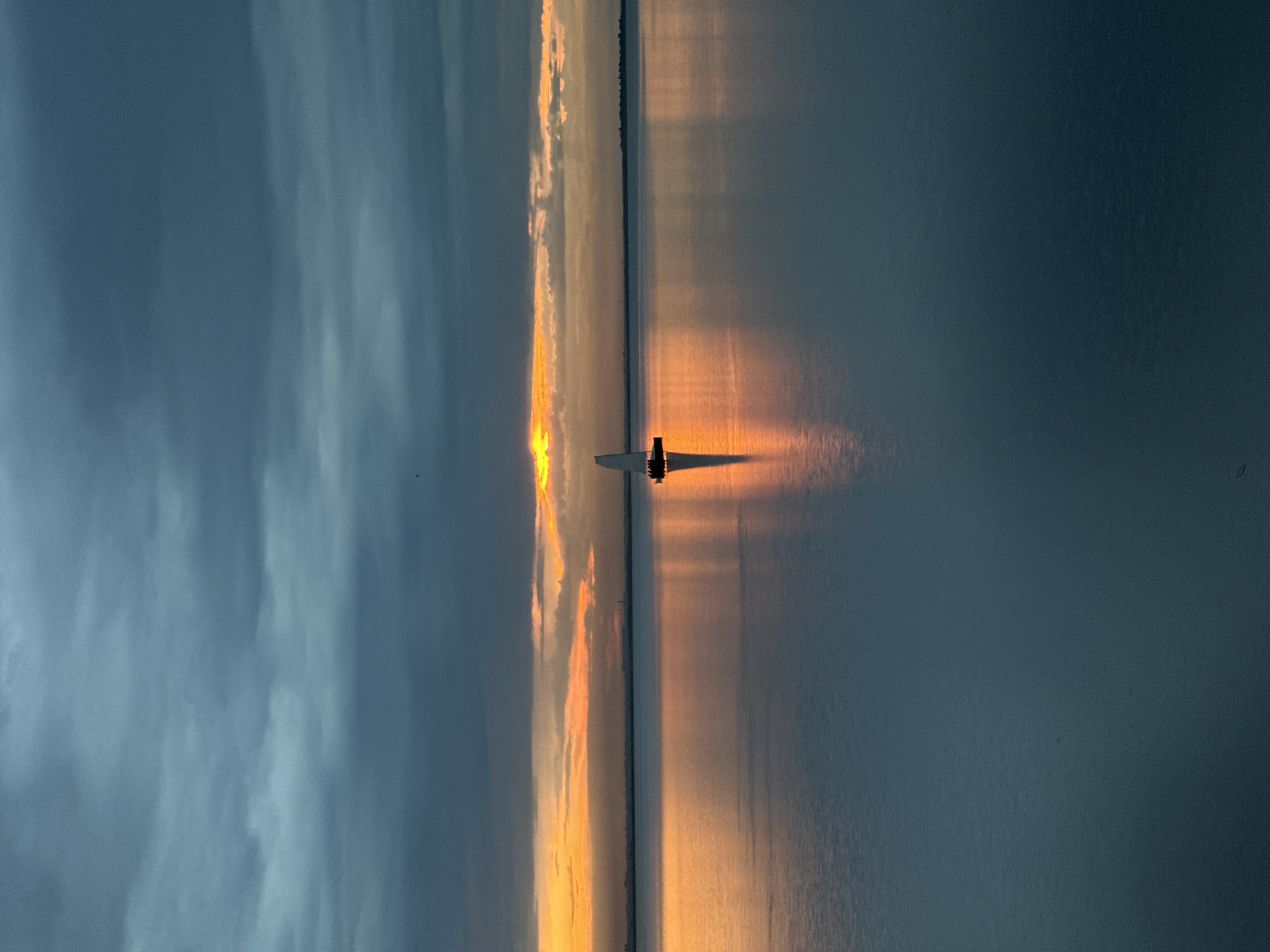 Stormy sunset over a Kokshetau lake, sailboat on calm water