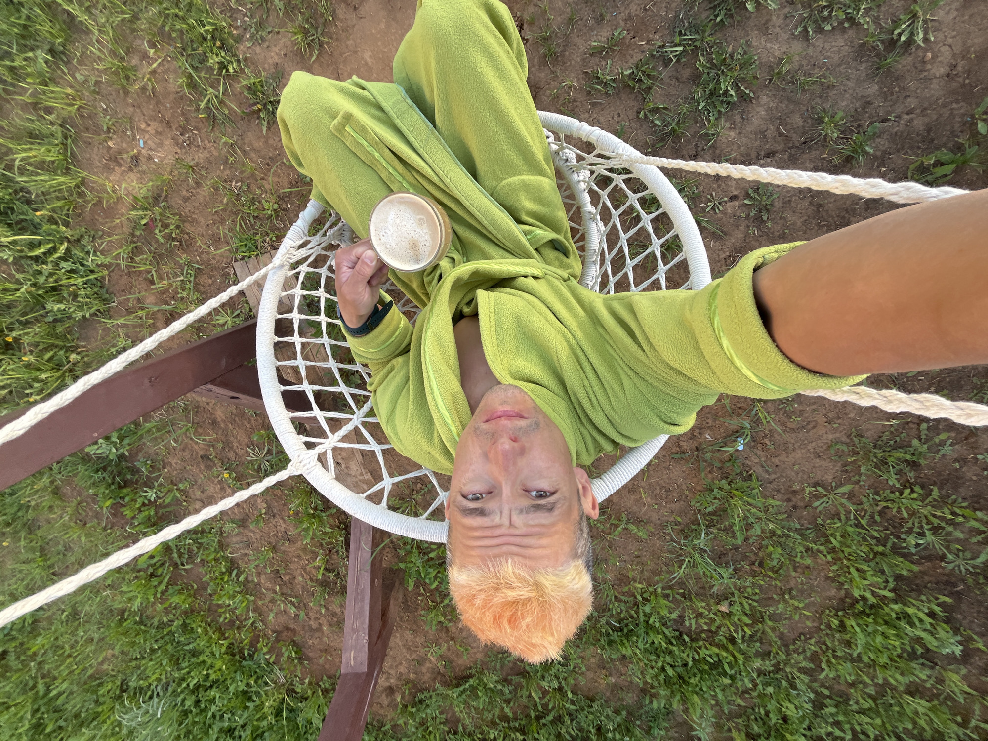 Man enjoys morning beverage in garden hammock in Chaikovsky
