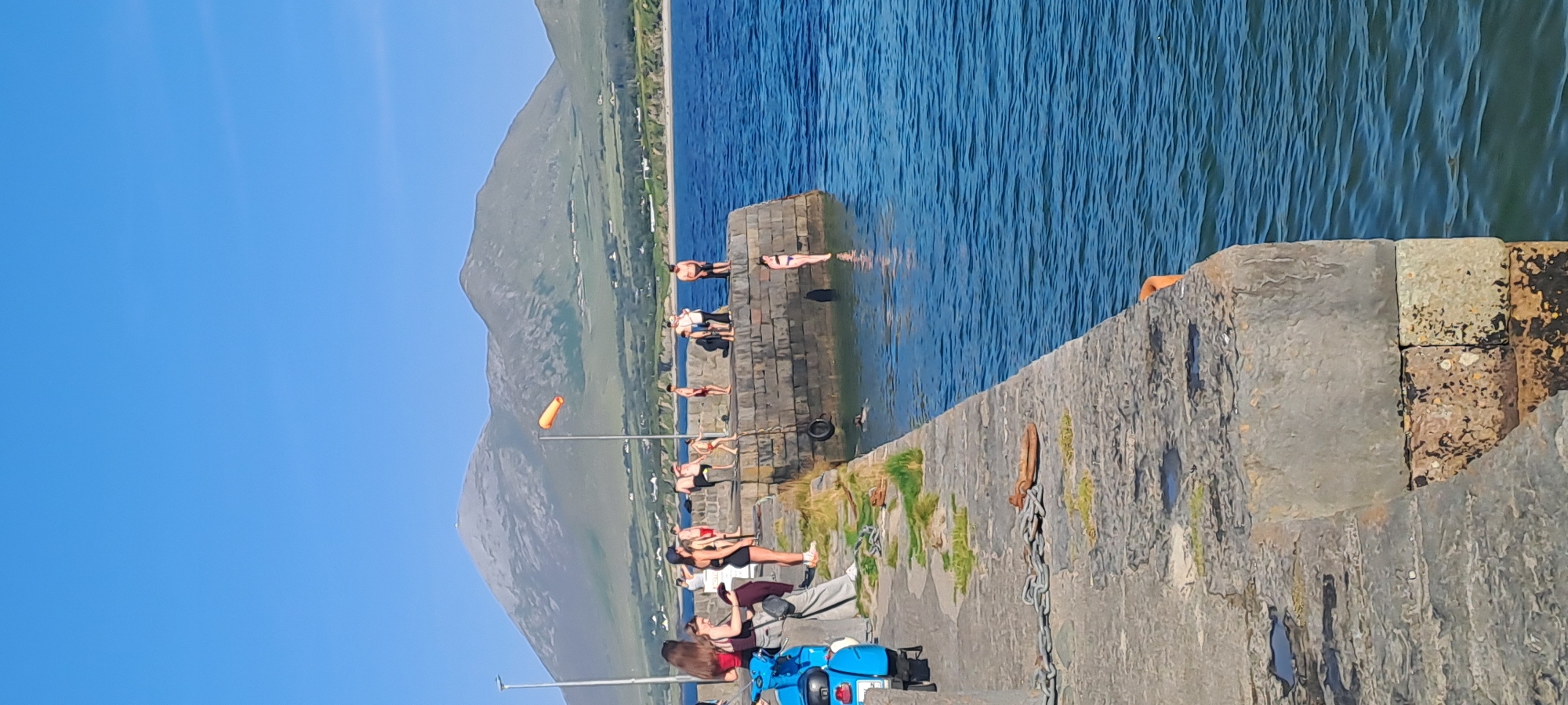 Sunny afternoon at an Irish coastal spot with pier and beach.