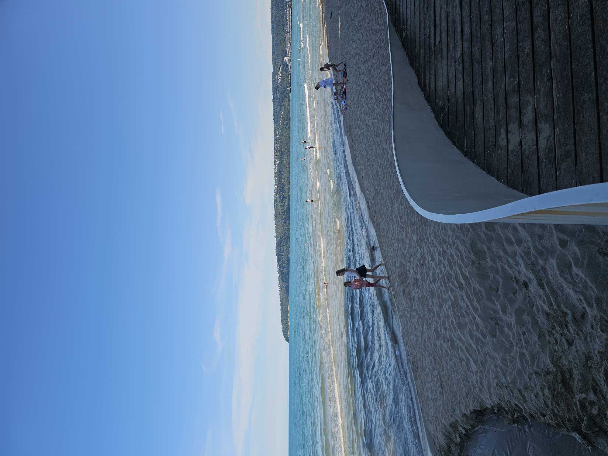 Sunny afternoon along a coastal promenade with cats and beach bars