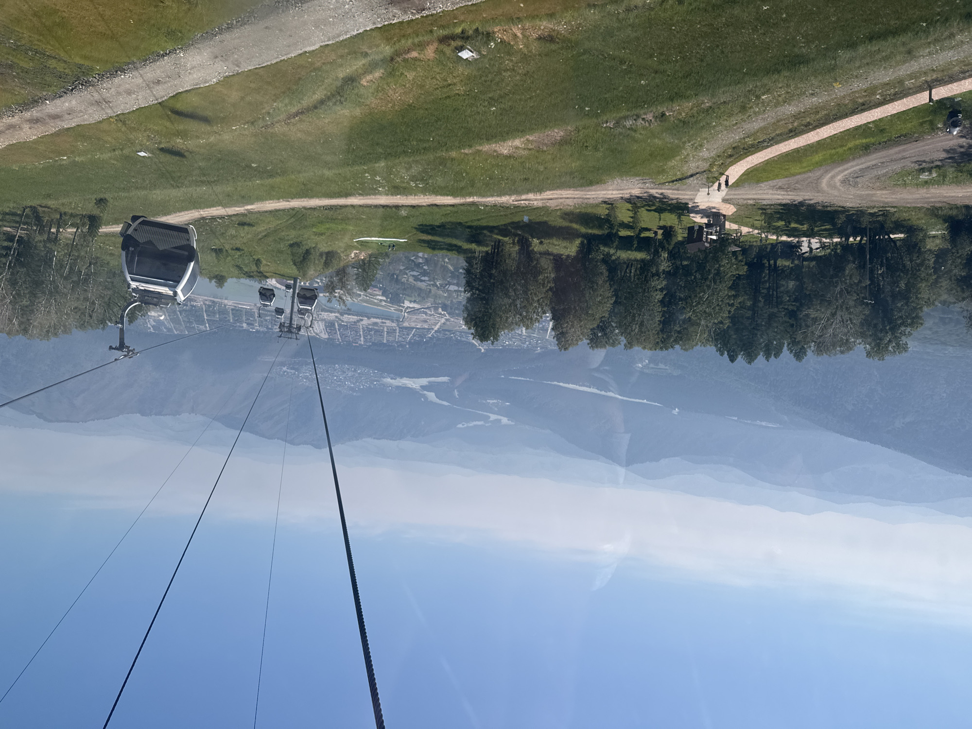 Cable car descending a green mountain slope in Ozernoe, Russia.