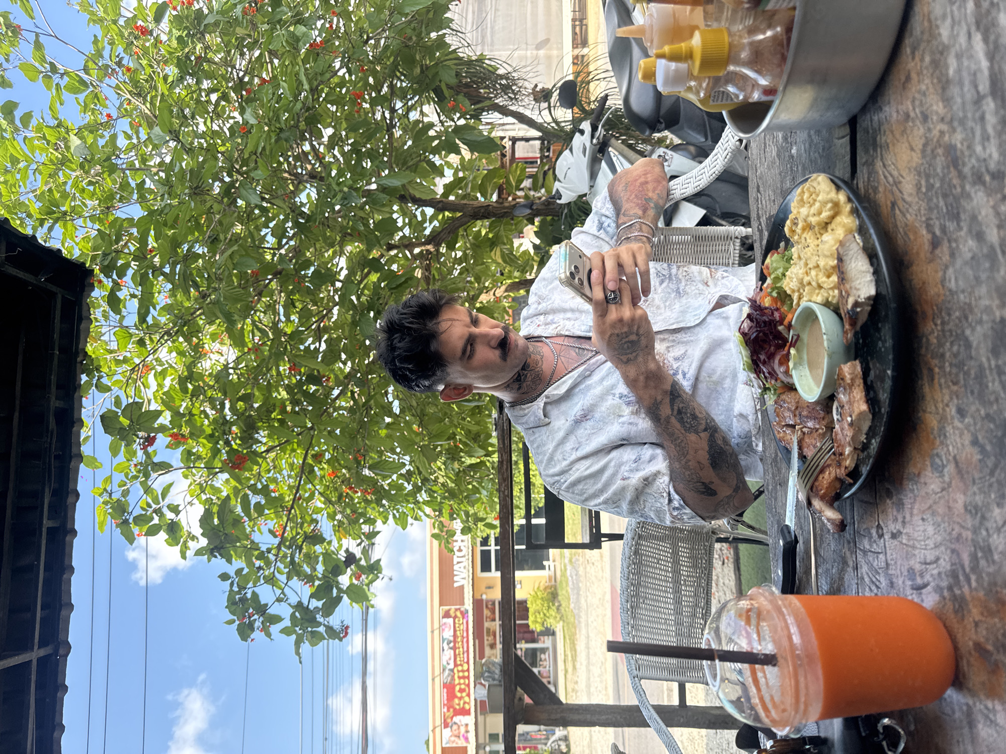 Man photographs food at outdoor table in Chalong, Thailand