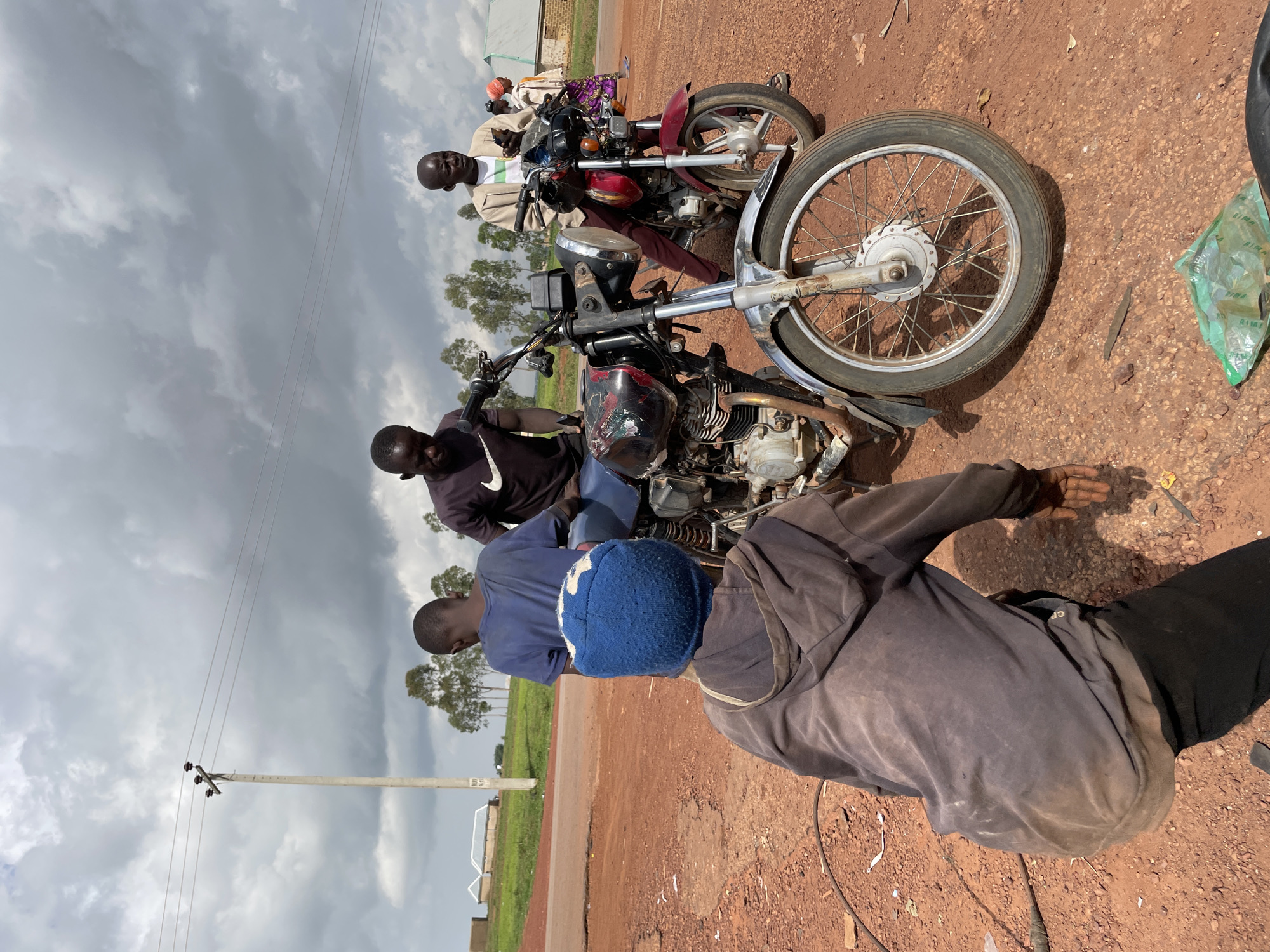 Roadside motorcycle repairs and daily movement in Wumat, Nigeria