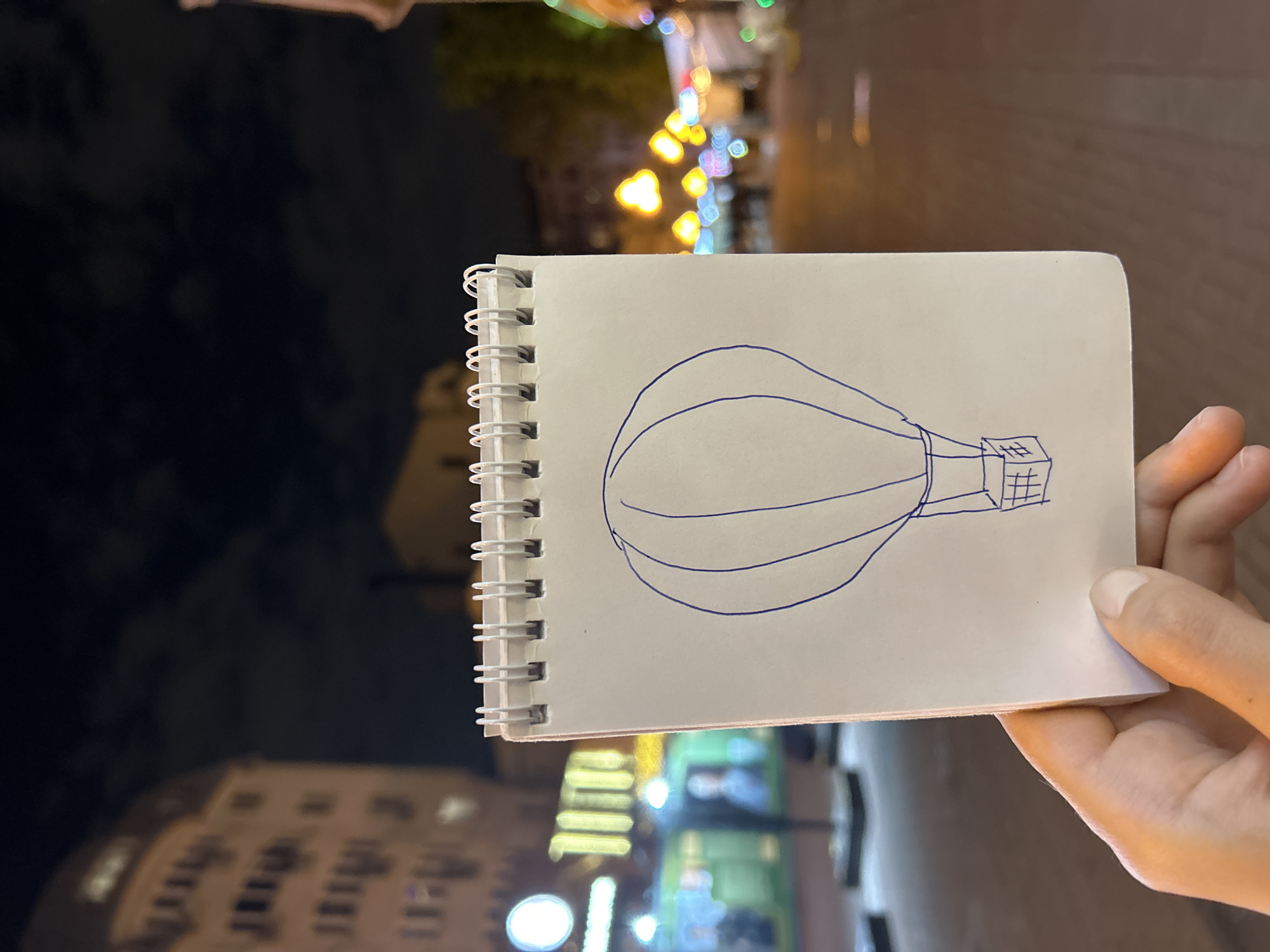 Night sketcher draws whimsical blue ink drawings on urban sidewalk