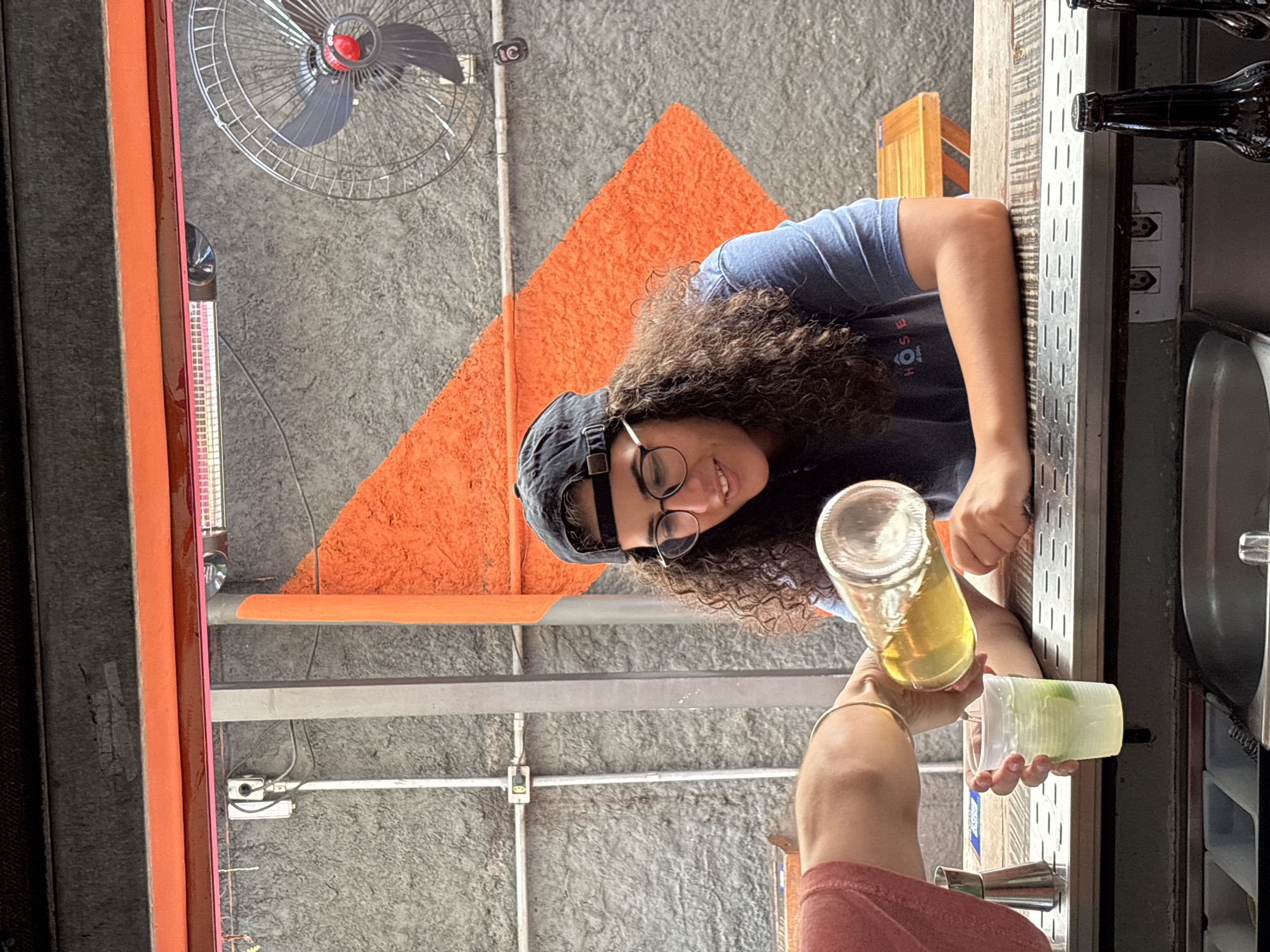 Person pours drink for another in São Paulo indoor gathering