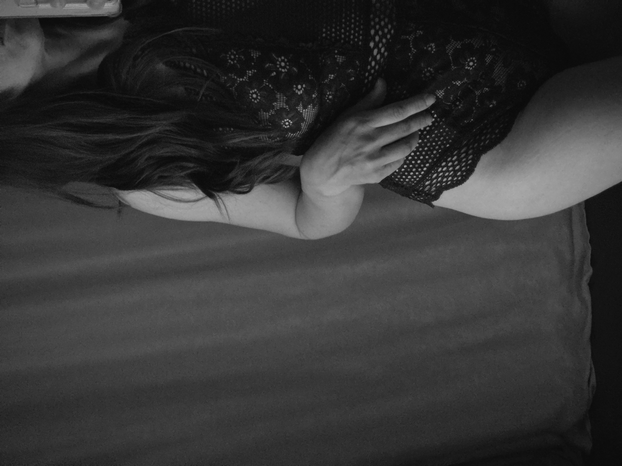 Woman photographed in intimate indoor setting wearing lace garment