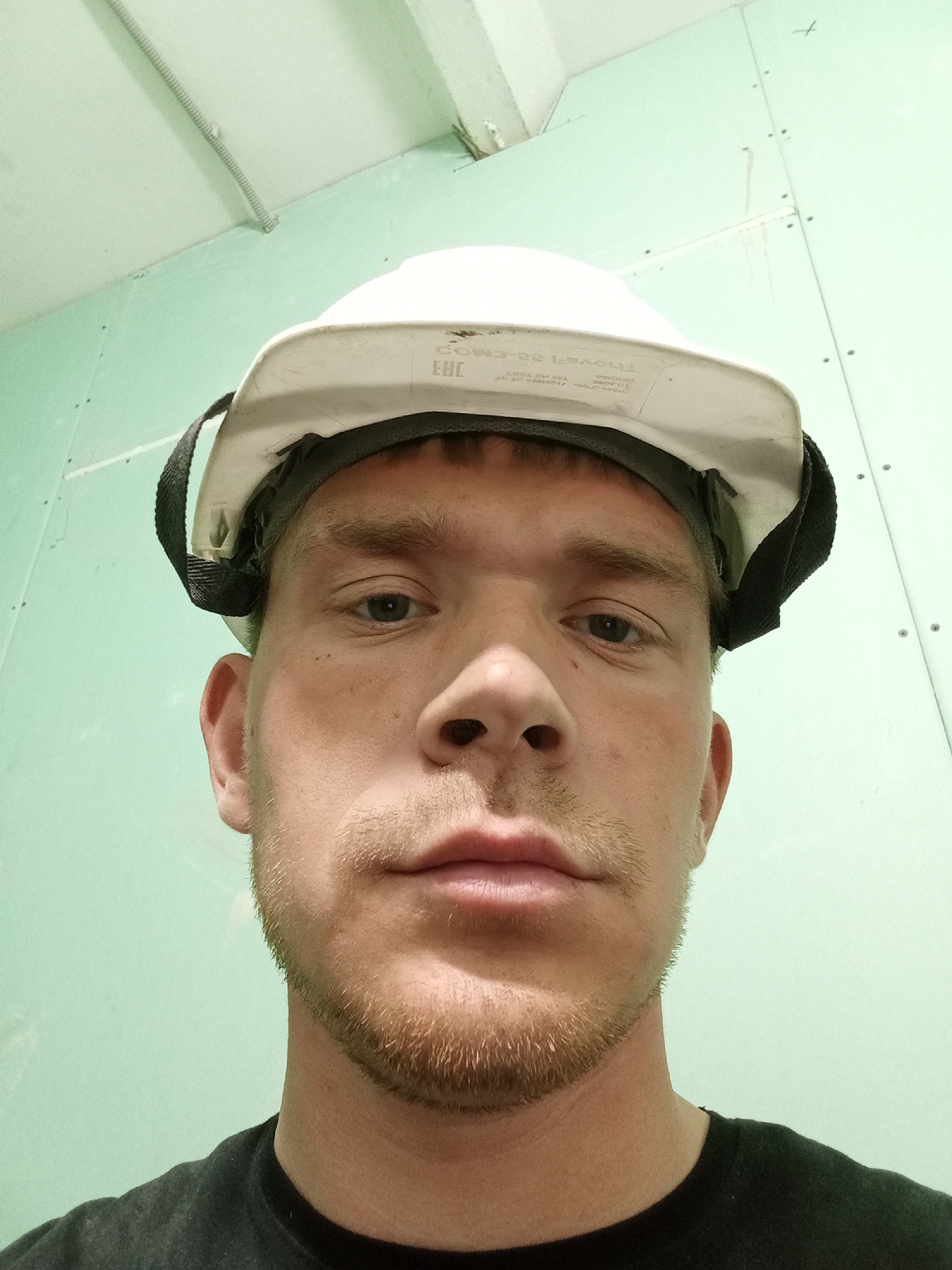 Construction Worker in White Hard Hat Photographed Against Green Wall