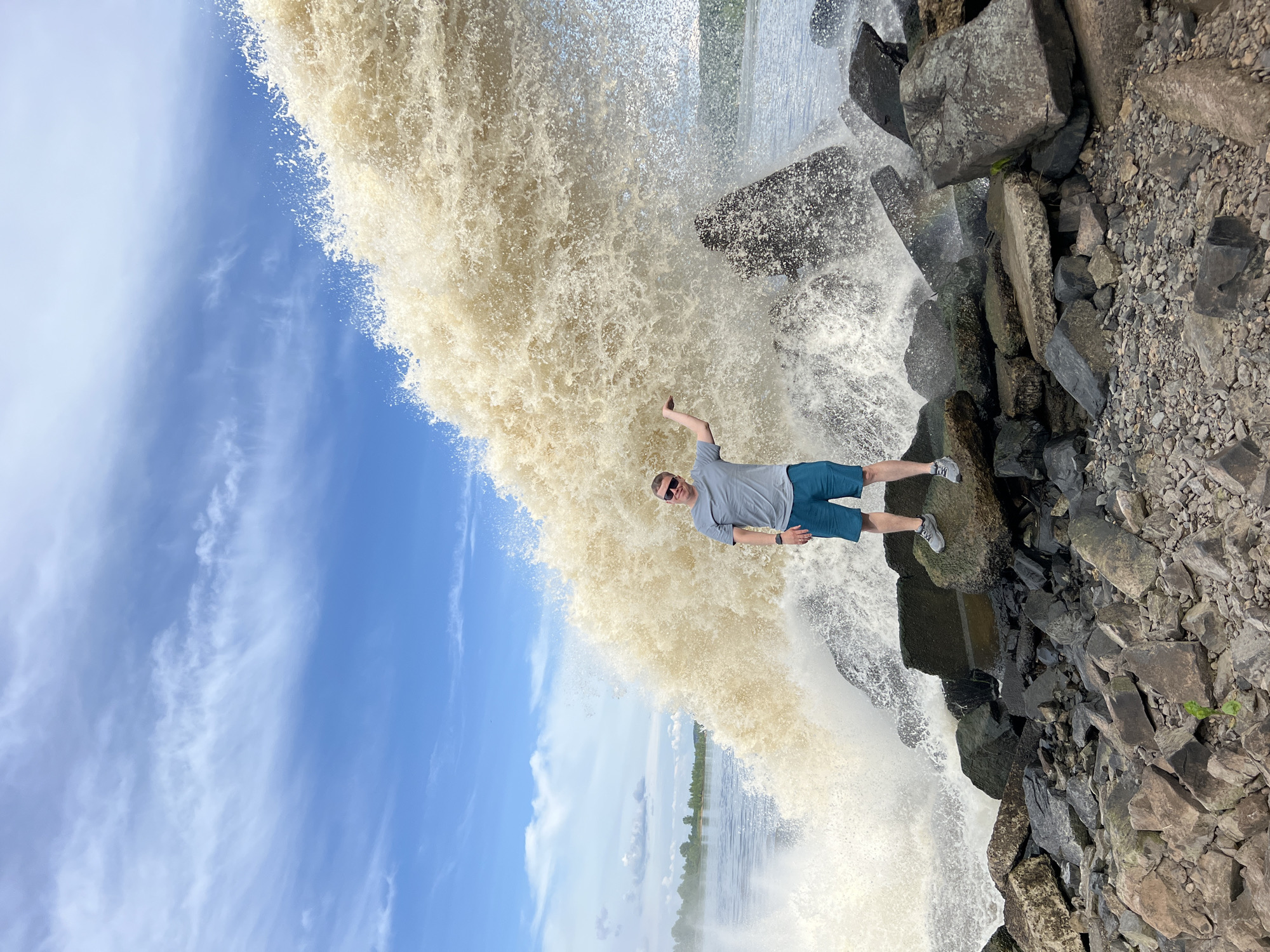 Man poses at powerful spillway waterfall in Chernushka, Russia