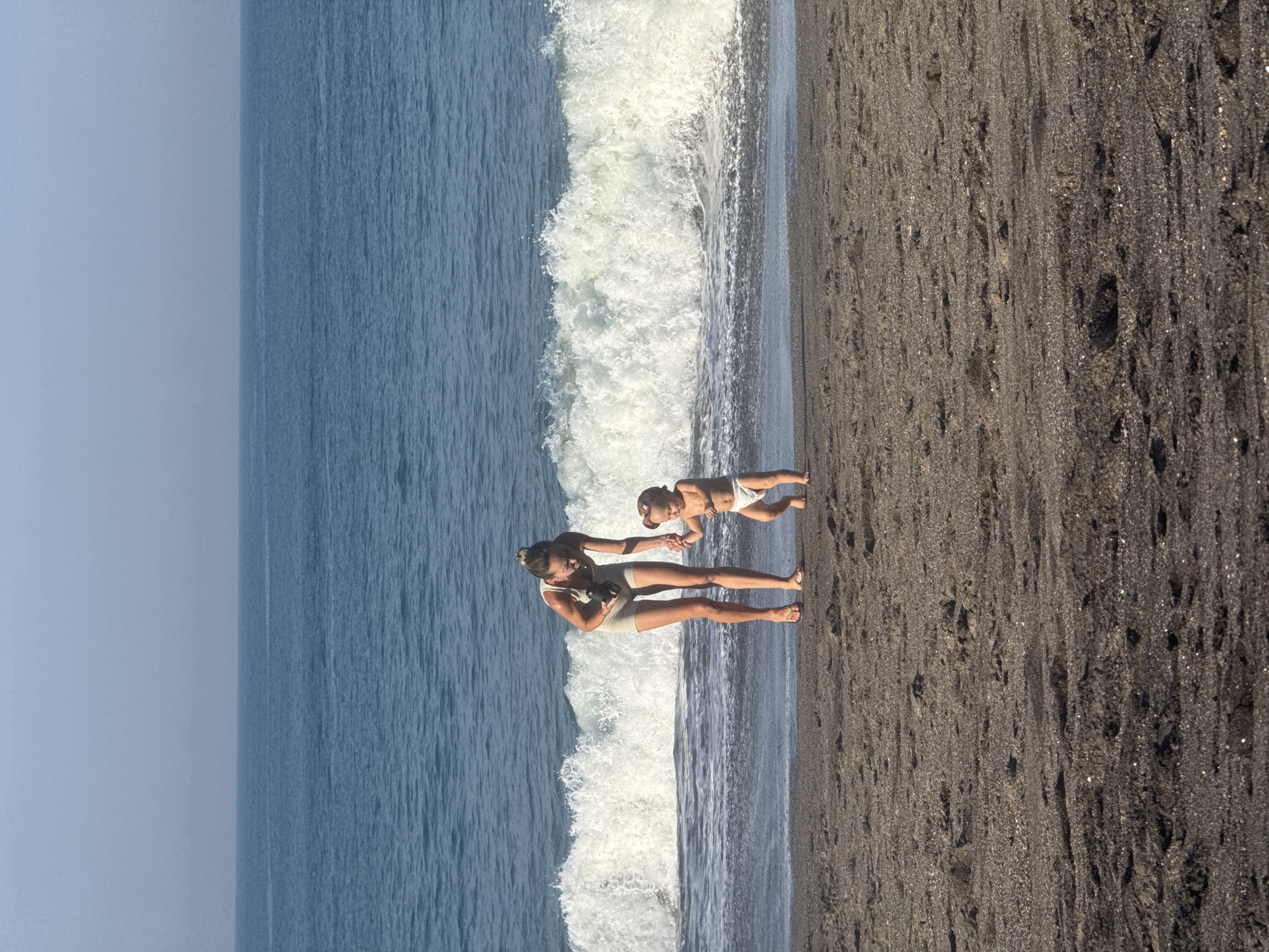 Woman and child enjoy early morning beach visit in Mengwi