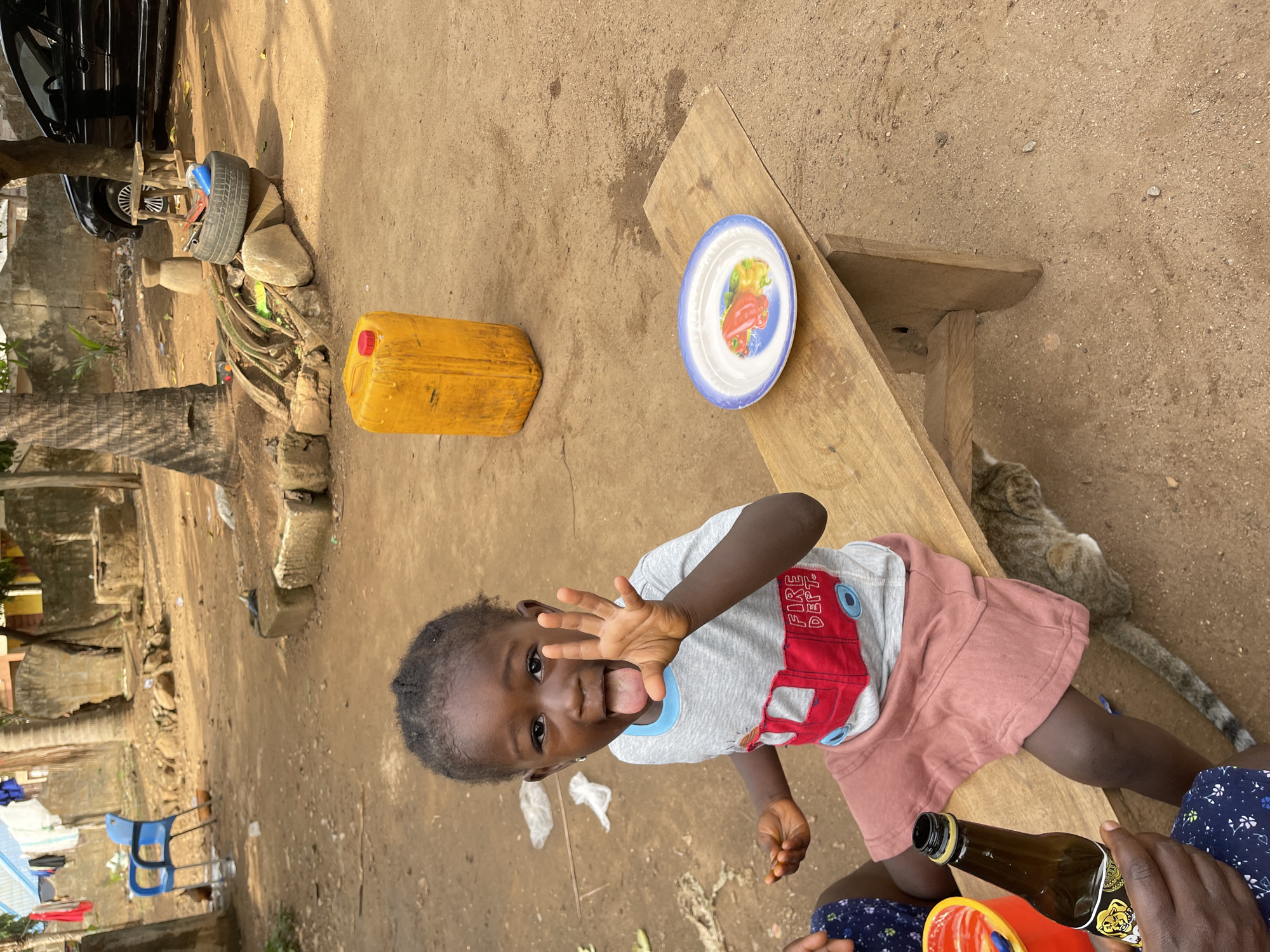 Child fed by caregiver on wooden bench in Akwanga