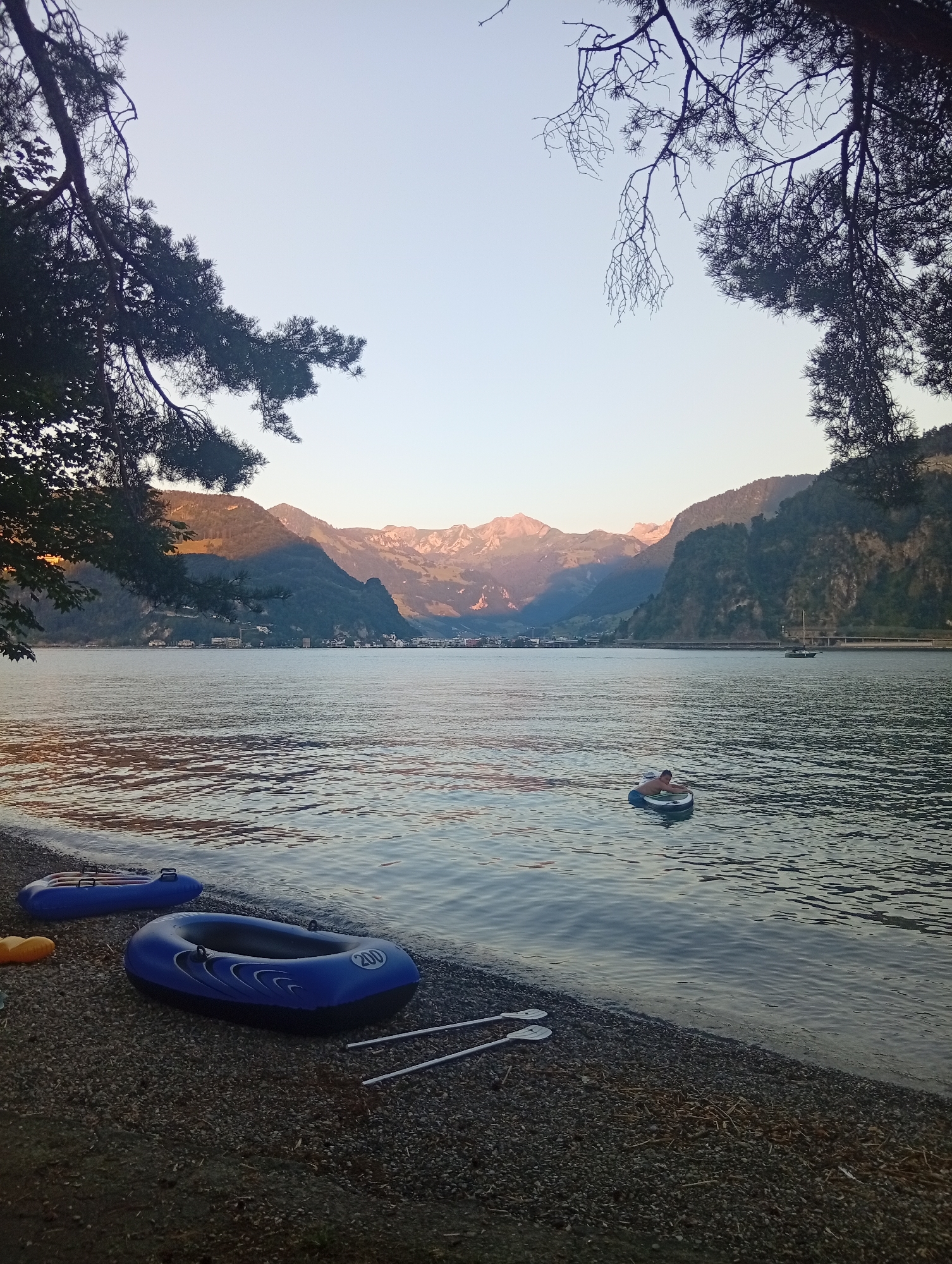 Inflatable boats resting on a Lake Lucerne pebble shore at dusk