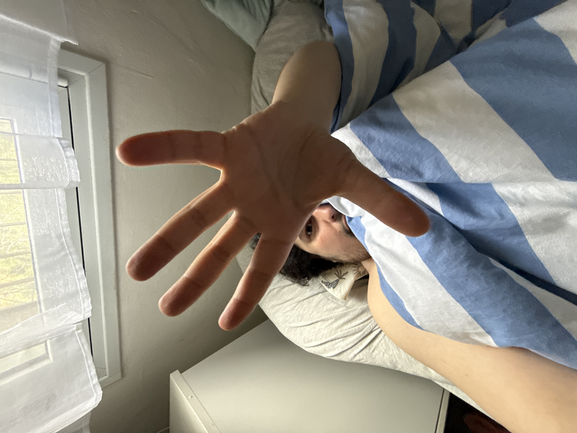 Person rests in bed with striped bedding in Jerusalem