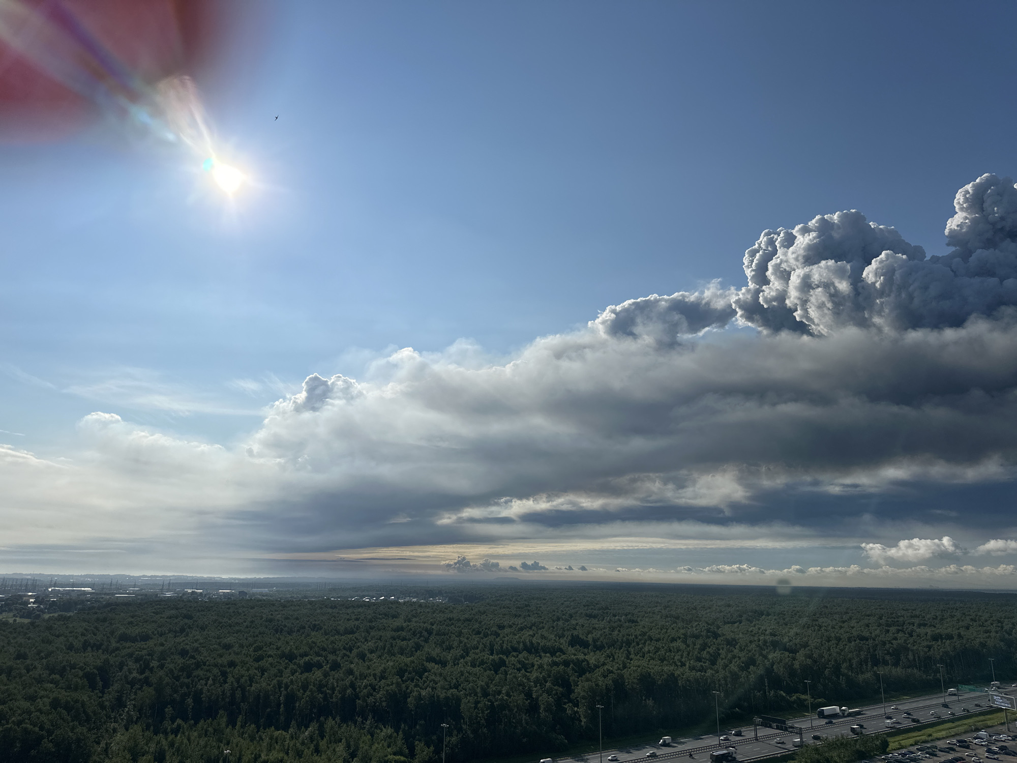 Dense forest fire sends heavy smoke toward nearby city skyline