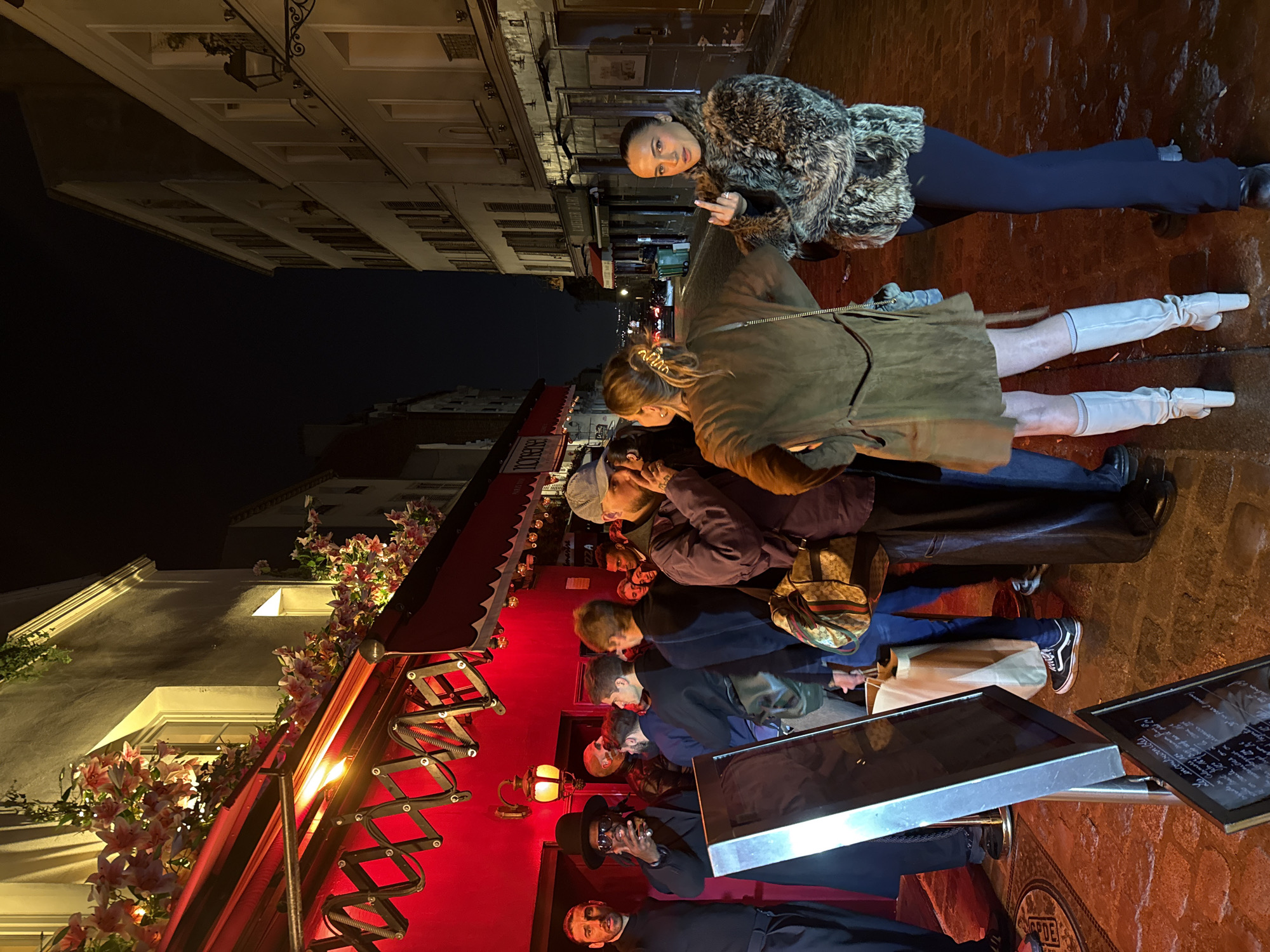 Nighttime gathering outside flower-decorated Paris storefront