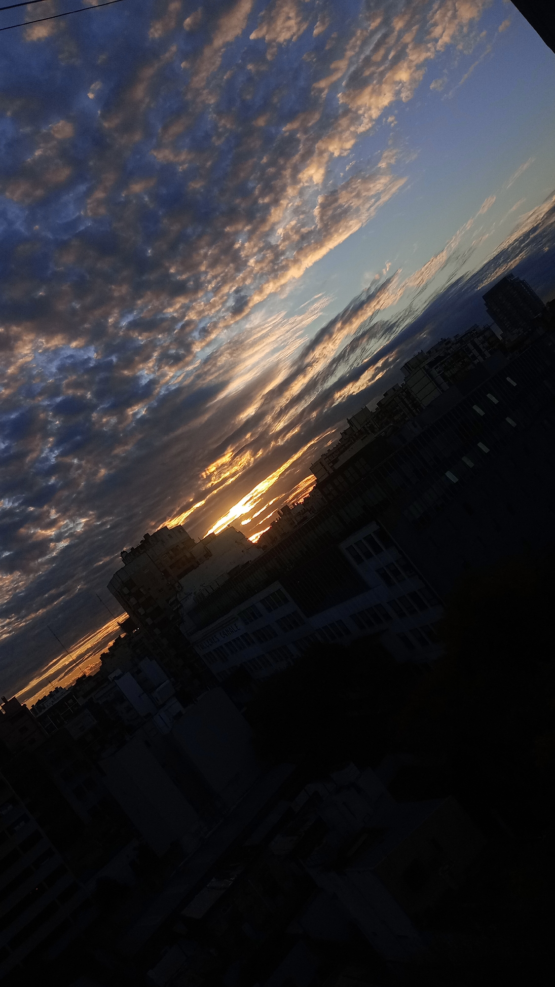 Dramatic sunset illuminates Buenos Aires skyline amid cloudy evening