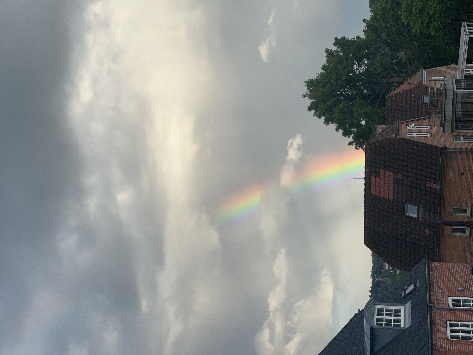 Rainbow over Vejle residential area through stormy clouds