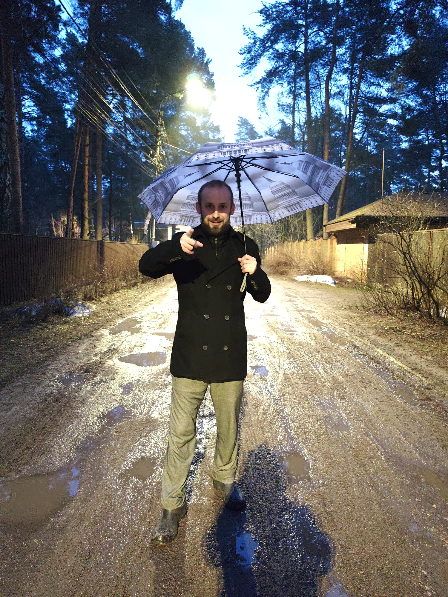 Man with American flag umbrella stands on muddy Russian street