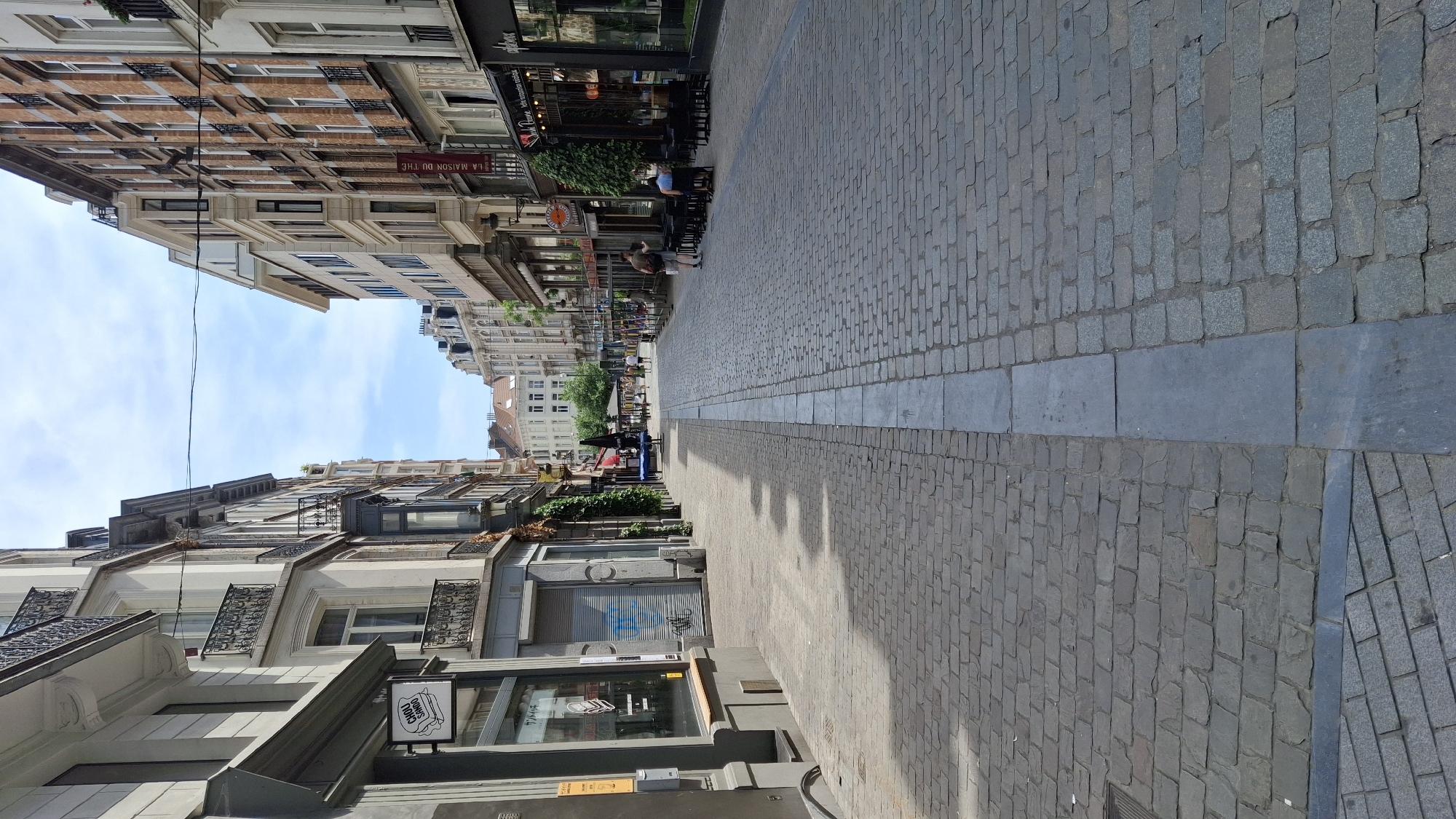 European city streets, transit stops, and storefronts on a summer afternoon