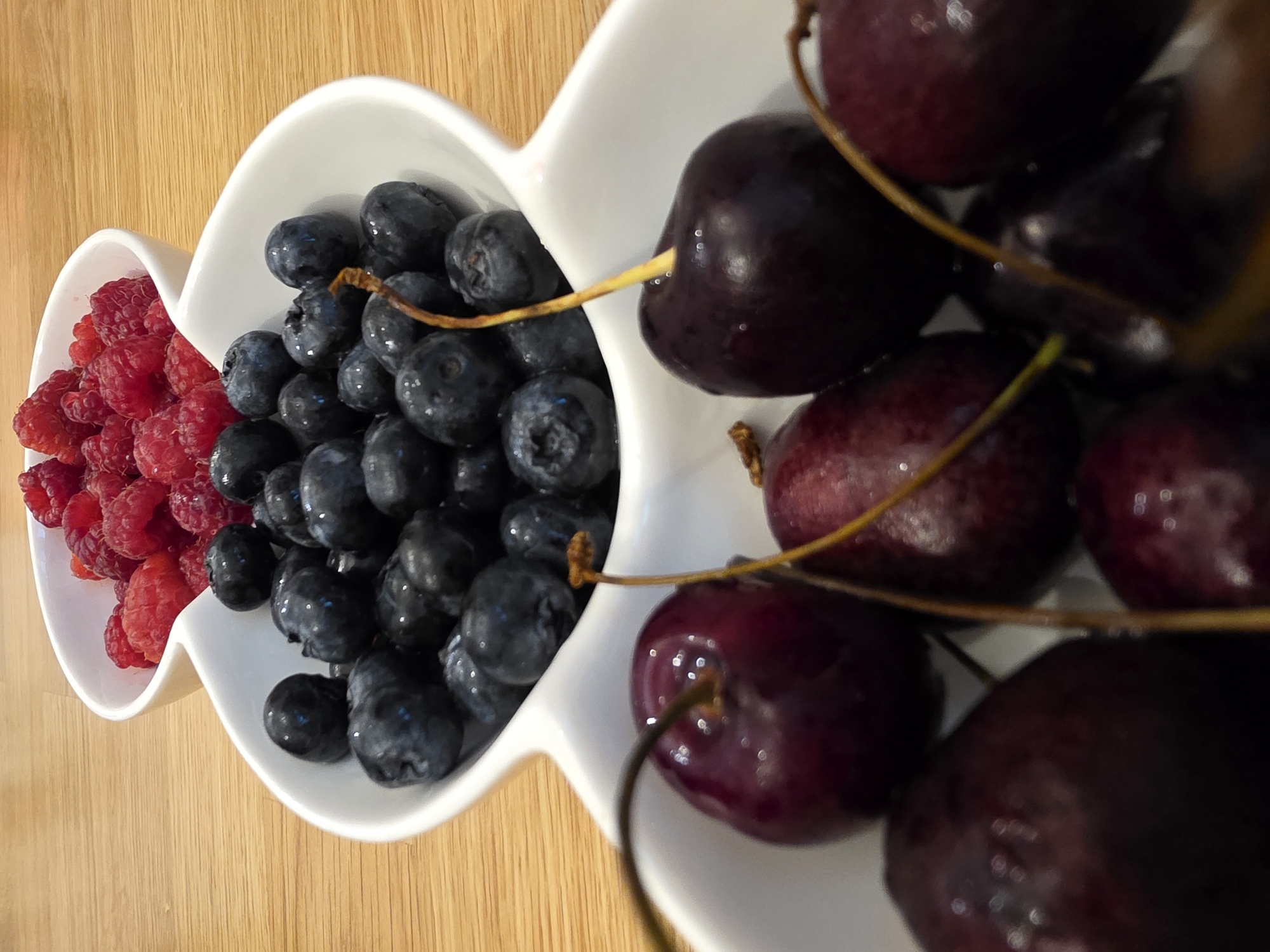 Fresh berries in ceramic bowls on a wooden surface