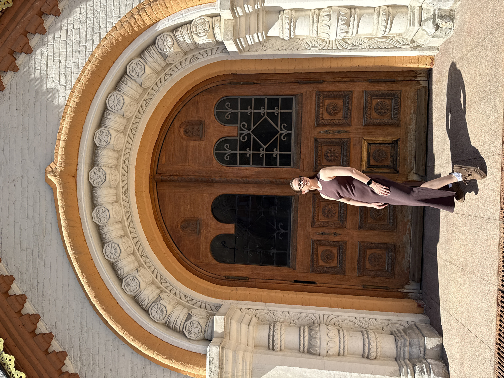 Woman in brown dress stands before ornate door in Moscow