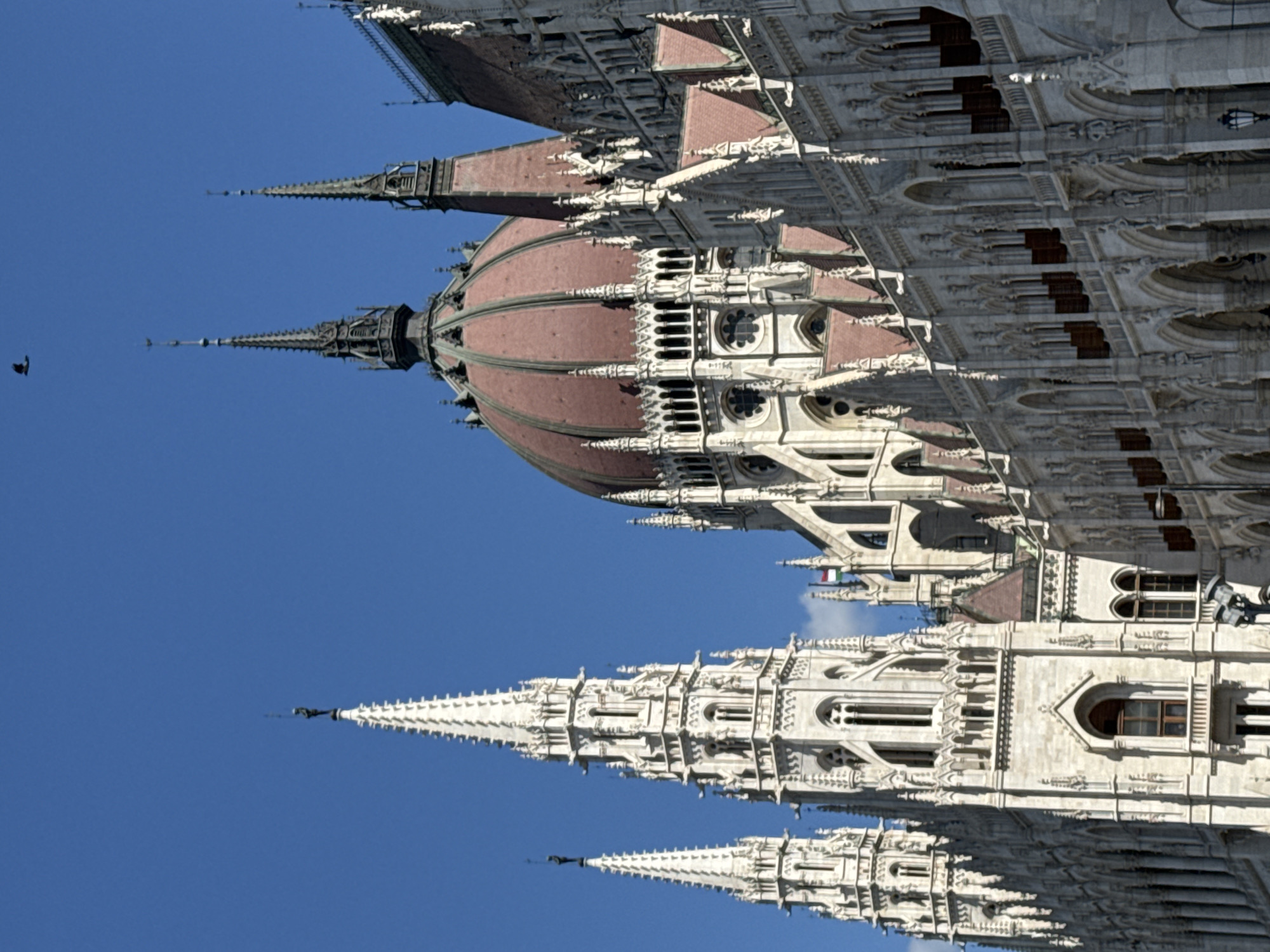 Tourist photographs Hungarian Parliament Building under clear Budapest skies