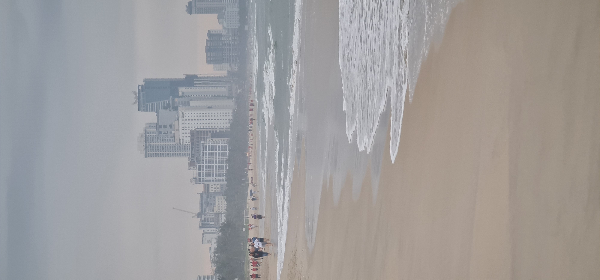 Evening beachgoers enjoy Đà Nẵng coastline under overcast skies