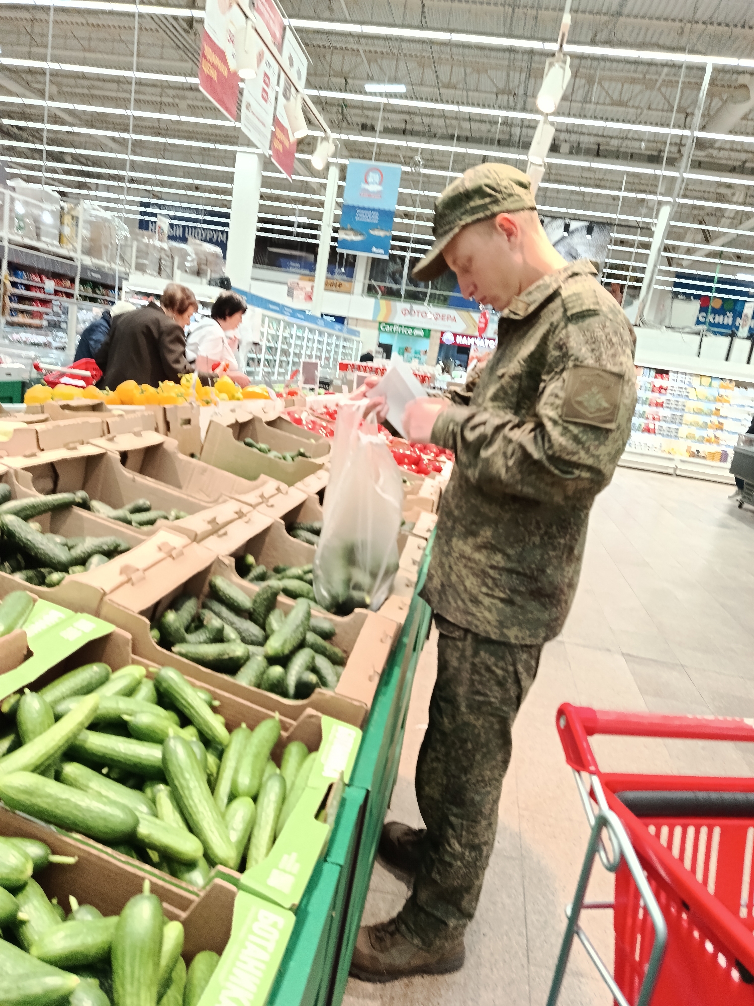 Military-dressed man shops vegetables at Moscow supermarket