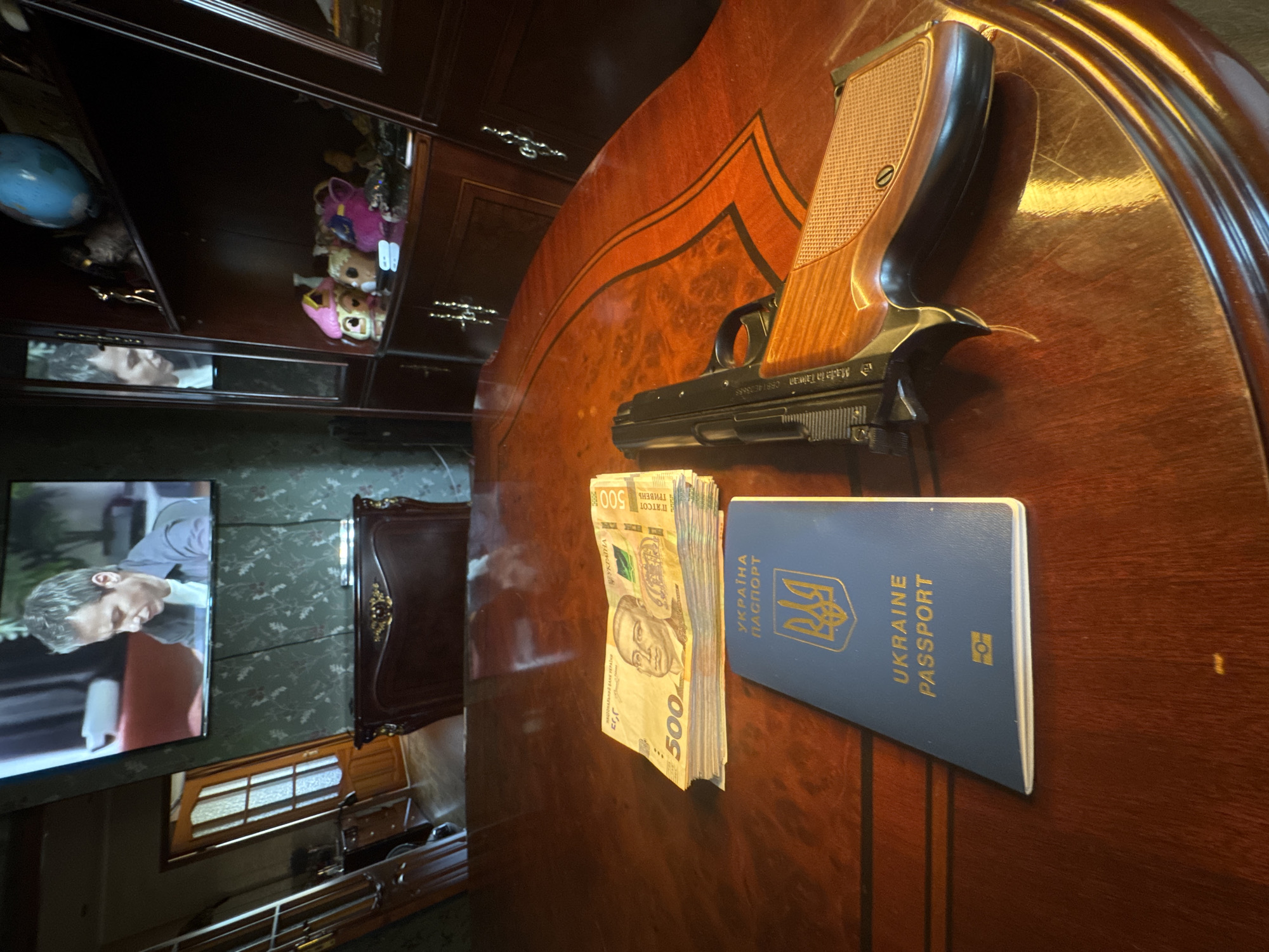 Cash, a firearm, and a passport staged across a Mykolaiv apartment