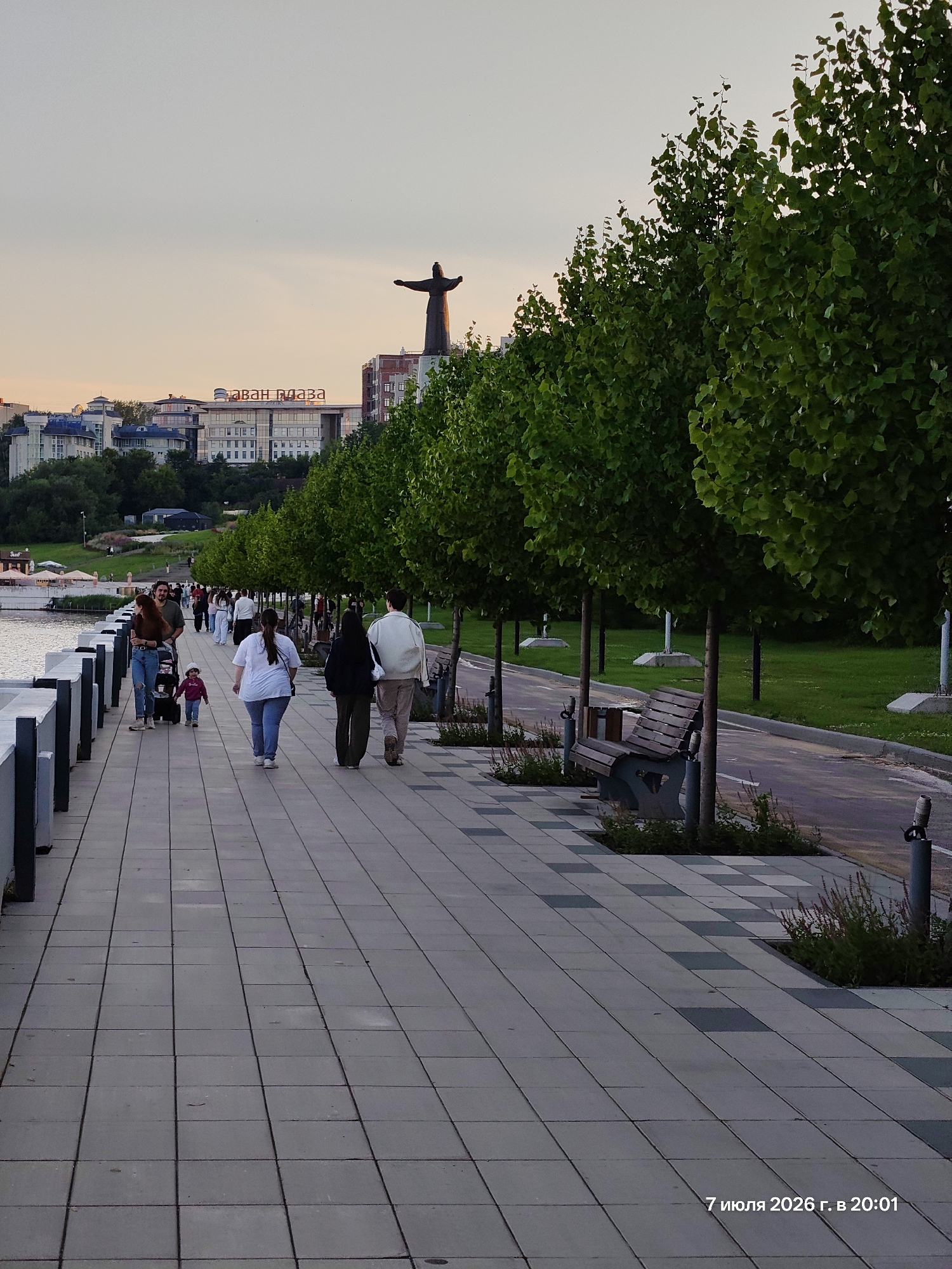 Riverside city at golden hour: promenades, cyclists, and a landmark statue