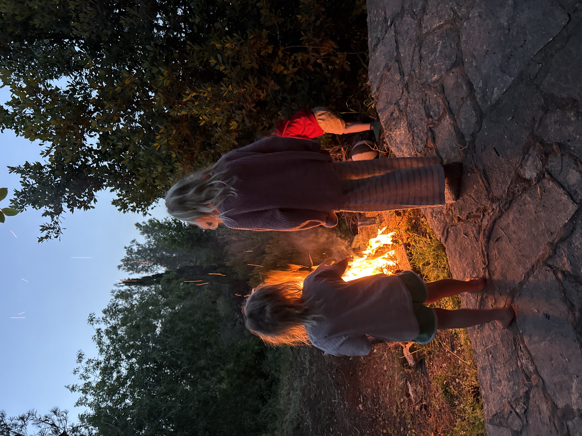 Children gather around campfire at twilight in Kfar Vradim