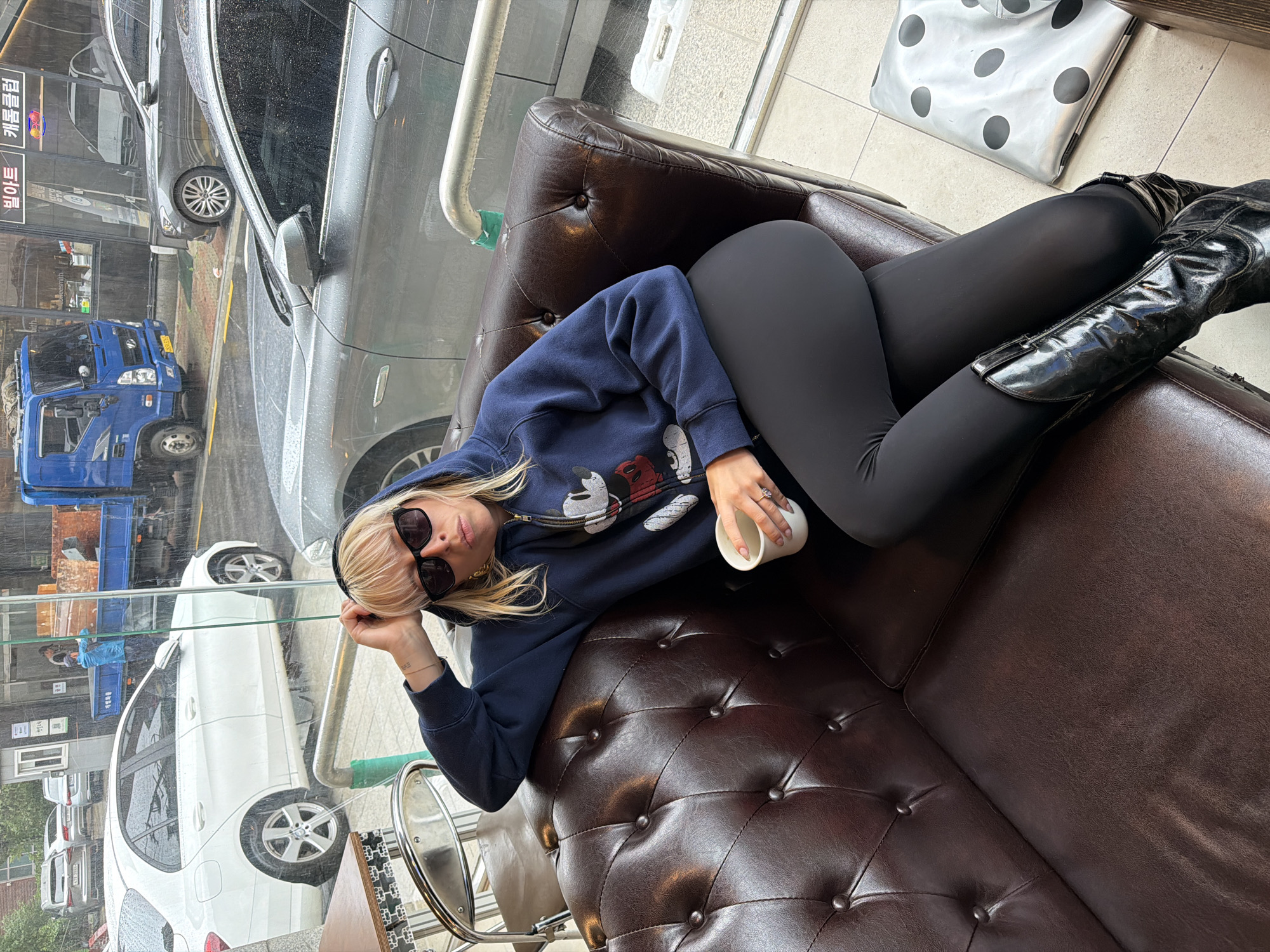 Woman in Mickey Mouse hoodie rests in Seoul cafe