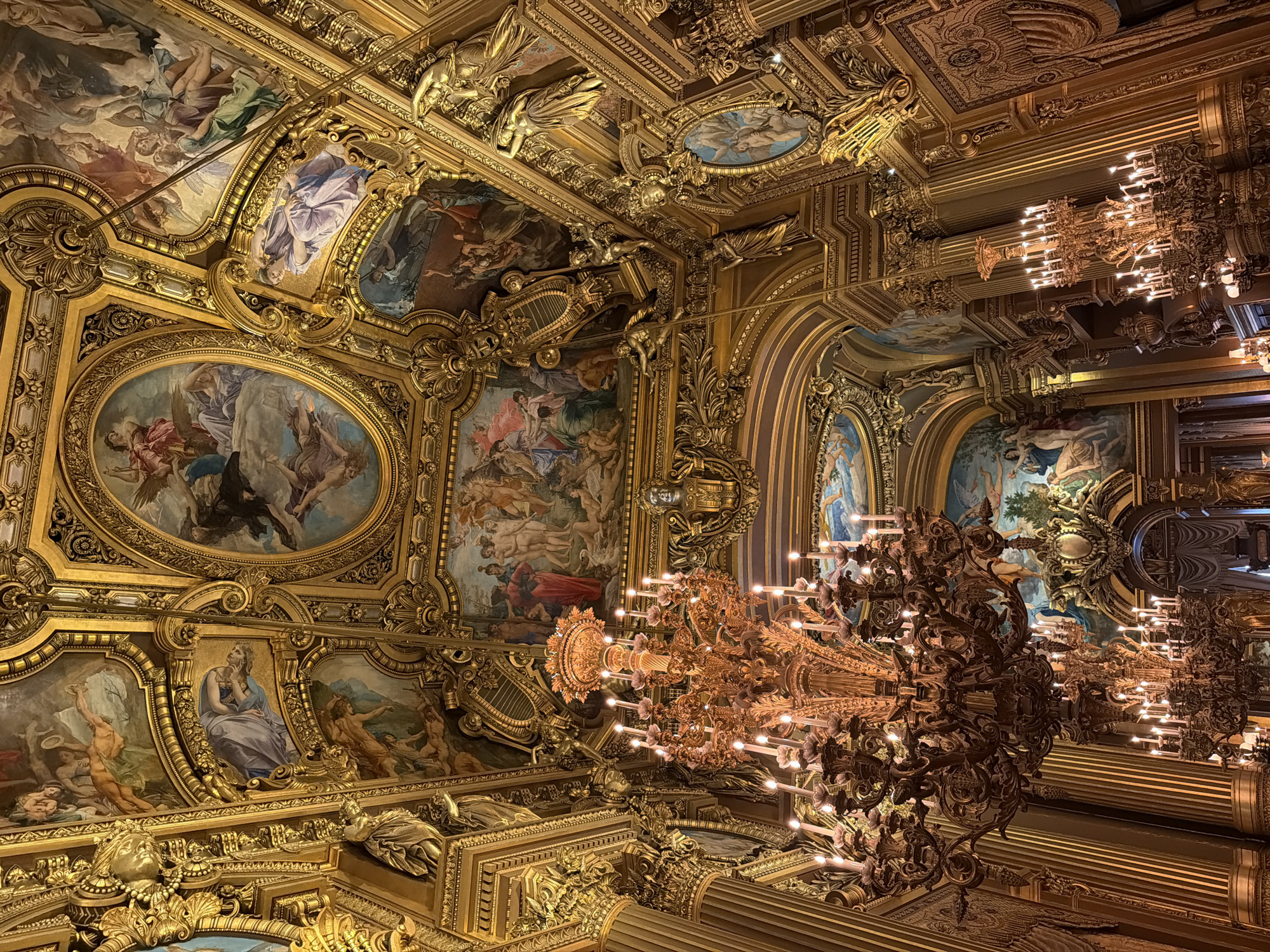 Visitor documents ornate Palais Garnier interior in Paris