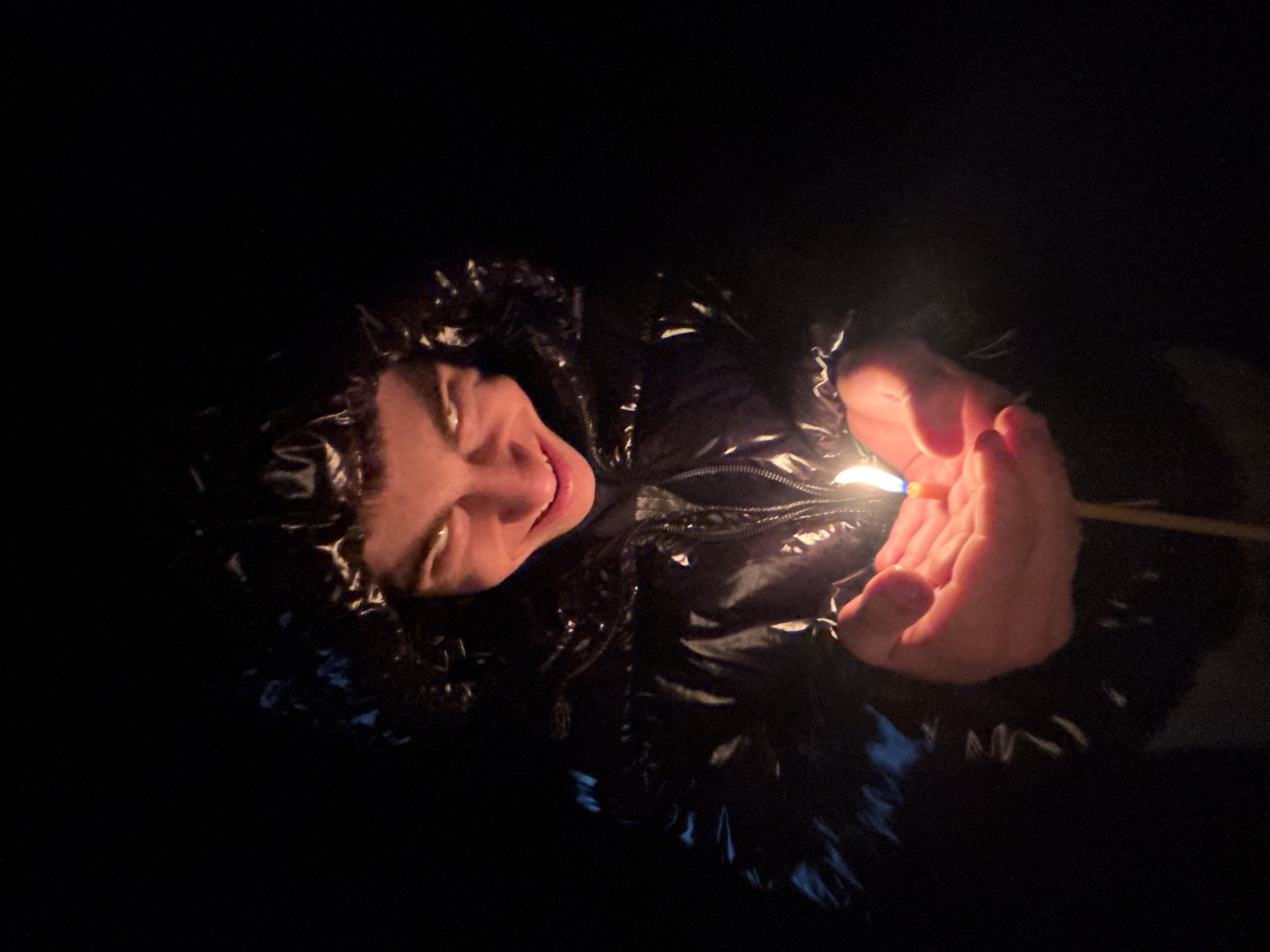 Woman holds lit match during nighttime walk in Lehchevo