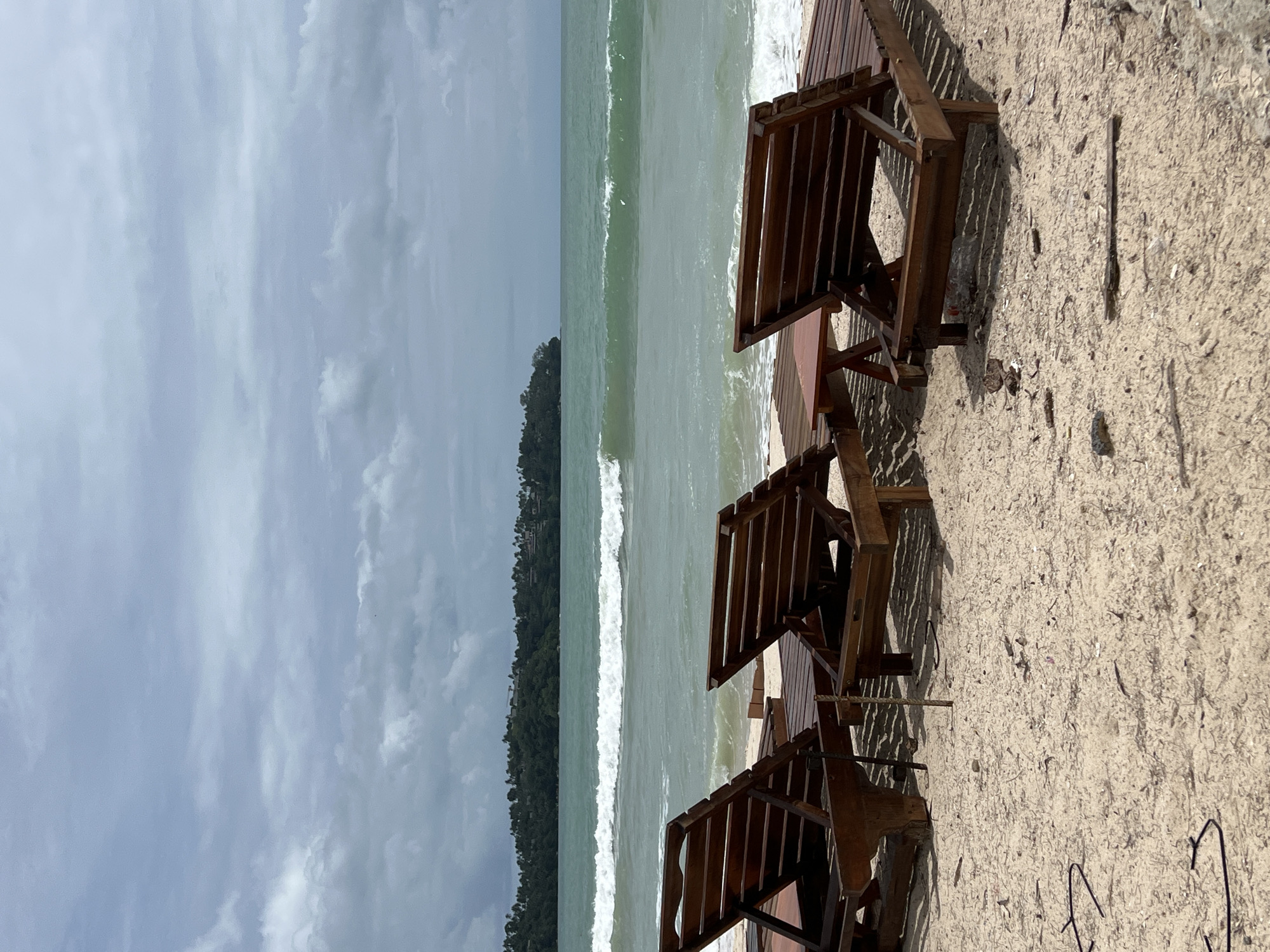 Beach scene captured with chairs, surfer, distant island