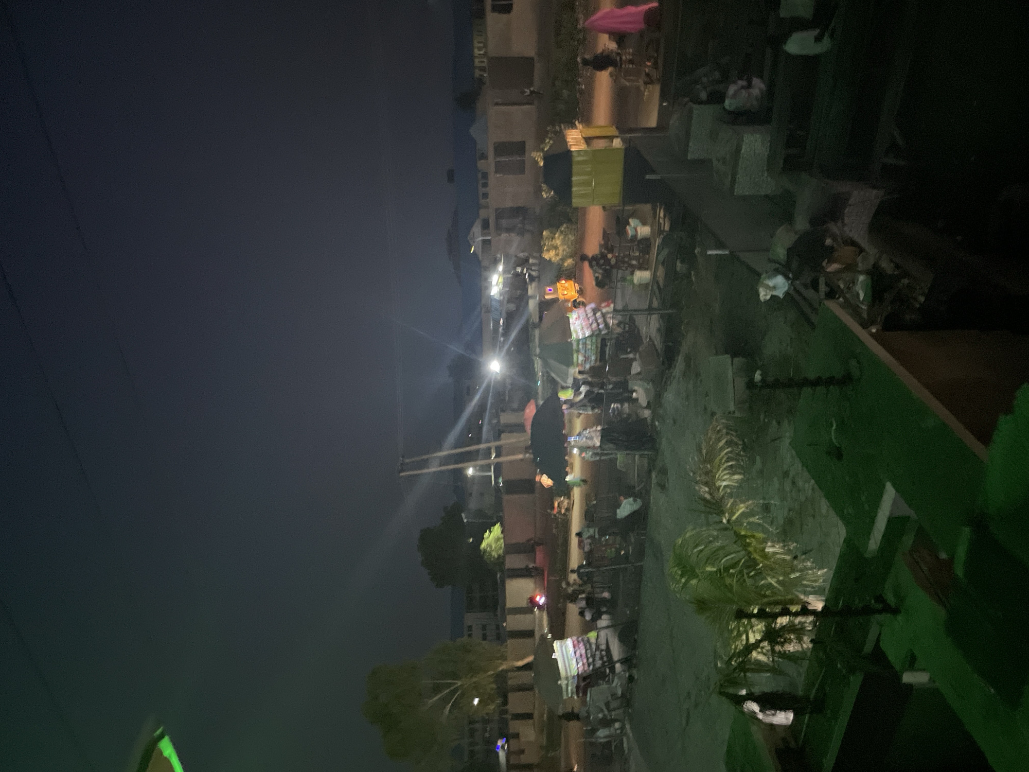 Dusk activity around a small urban compound with street food and market stalls