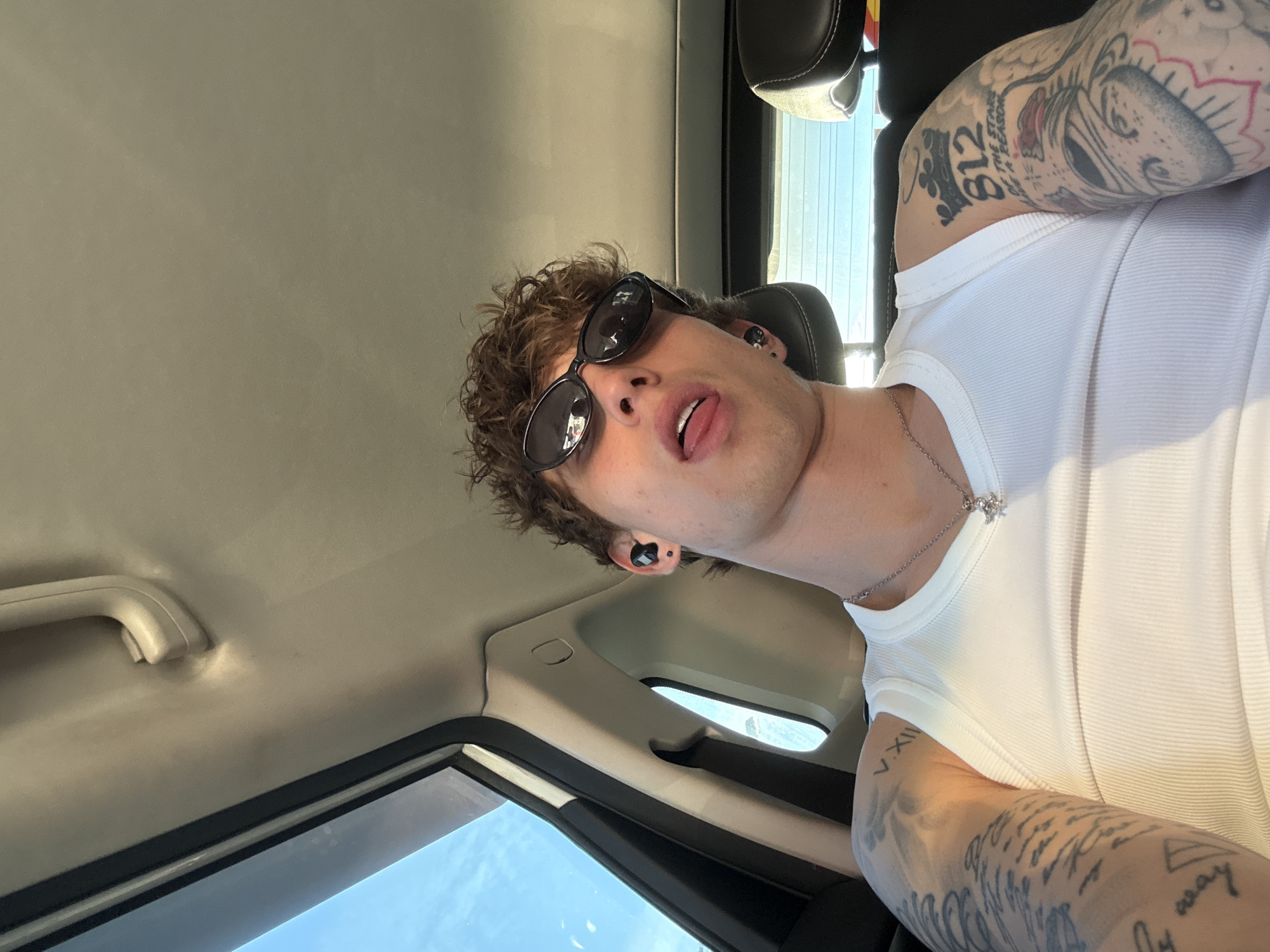 Tattooed man in white tank top observed in car