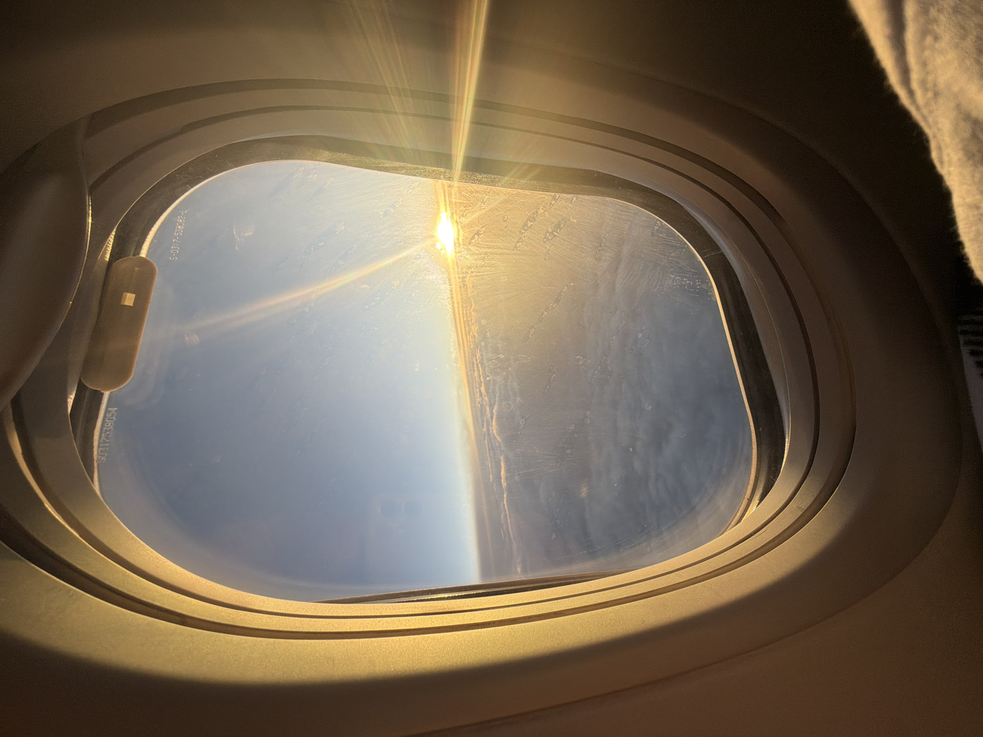 Passenger documents sunrise flight over Russian cloudscape from airplane window